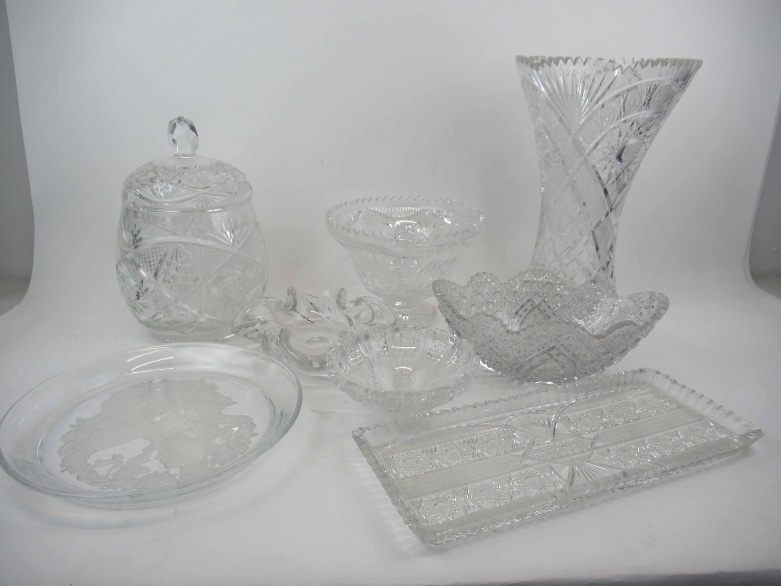 Group of Cut and Pressed Glass Table Articles: Group of Assorted Cut and Pressed Glass Table Articles. Including barrel shaped lidded punch bowl, vase, footed bowl, compote, tray and Lalique style plate, Used condition, wear, worn, some chips.
