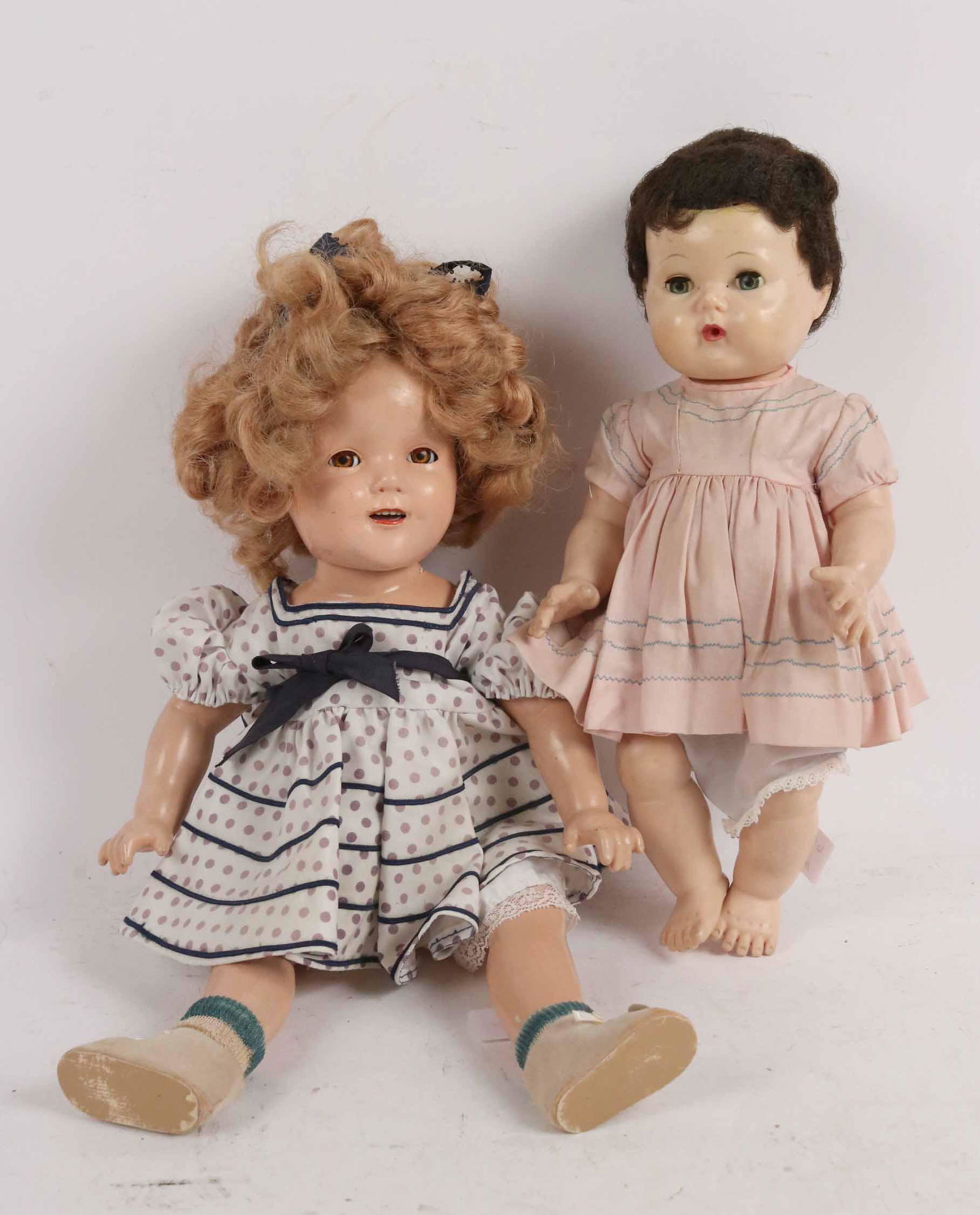 Shirley Temple Doll Ideal N. & T.C.: Composition synthetic rewigged and redressed. Together with an American character doll with blue eyes and brown curly hair. Condition: Crack at neck. Size: 19-1/2"l
