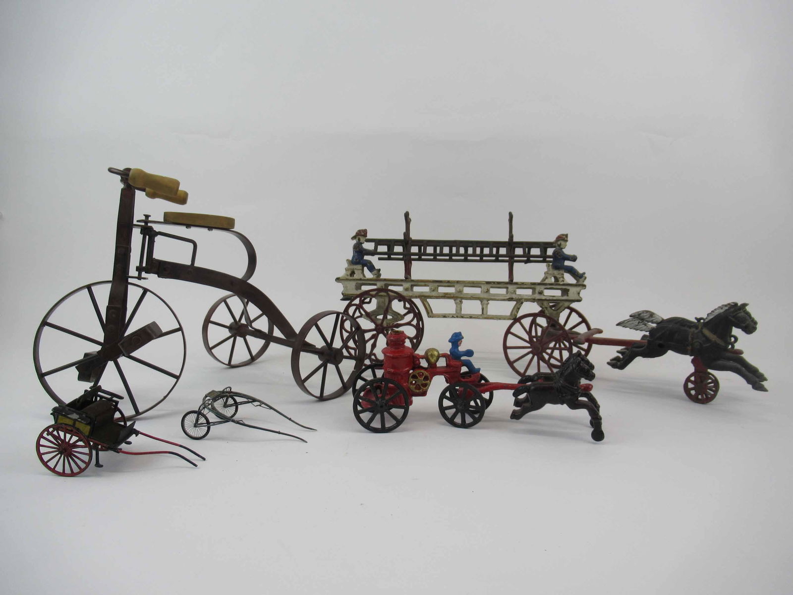 Cast Iron Horse Drawn Fire Department Truck: Cast Iron Horse Drawn Fire Department Ladder Truck with removable ladders. Together with a Cast iron pumper and a metal tricycle and 2 miniature Sulky's. Used condition, wear, worn, paint loss.Ladder