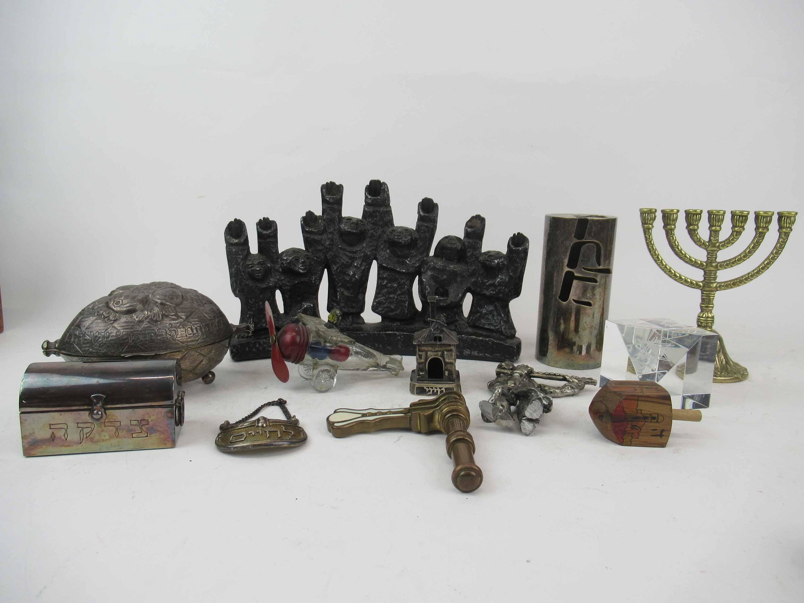 Group of Assorted Judaica Articles: Group of Assorted Judaica Articles. Including Ellen Lord Metal Brutalist Menorah, Brass Menorah, Spirit of good will airplane, flute player sterling silver, fiddler on the roof, Sterling silver decant
