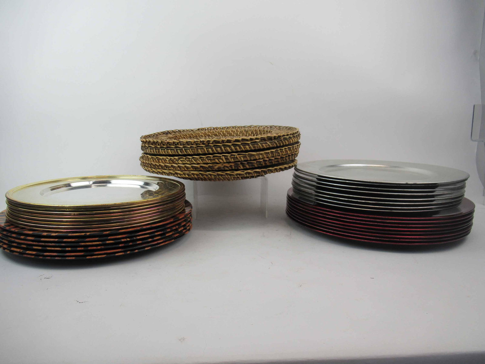 Group of Assorted Table Chargers: Group of Assorted Table Chargers. Including 5 rattan, 8 silver tone metal chargers with gold rim, 6 tiger print plastic chargers, 8 silver tone plastic chargers and 8 red tone plastic chargers. Larges