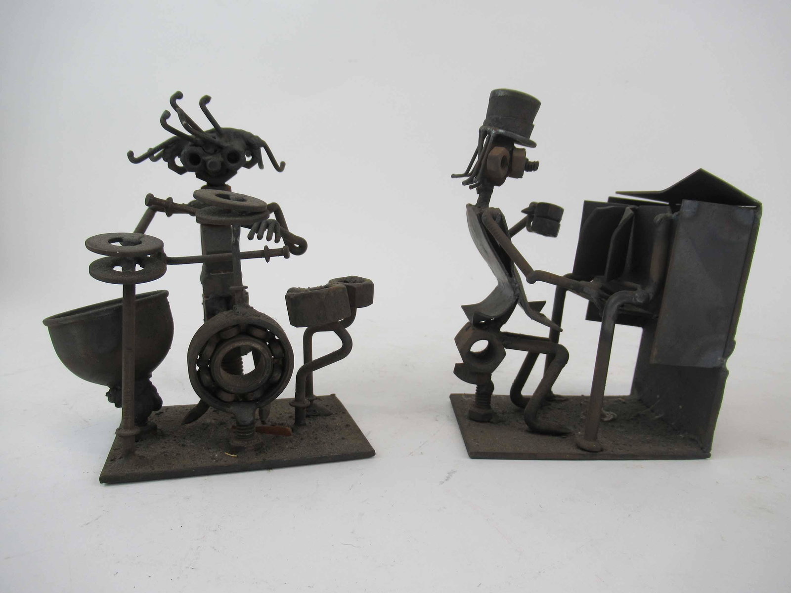 Pair of Metal Work Reclaimed Garage Sculpture: Pair of Metal Work Reclaimed Garage Sculpture depicting a drummer and piano player. Signed by artist. Used condition, wear, worn. largest size 6 1/2" tall x 4 1/2" deep x 3" wide