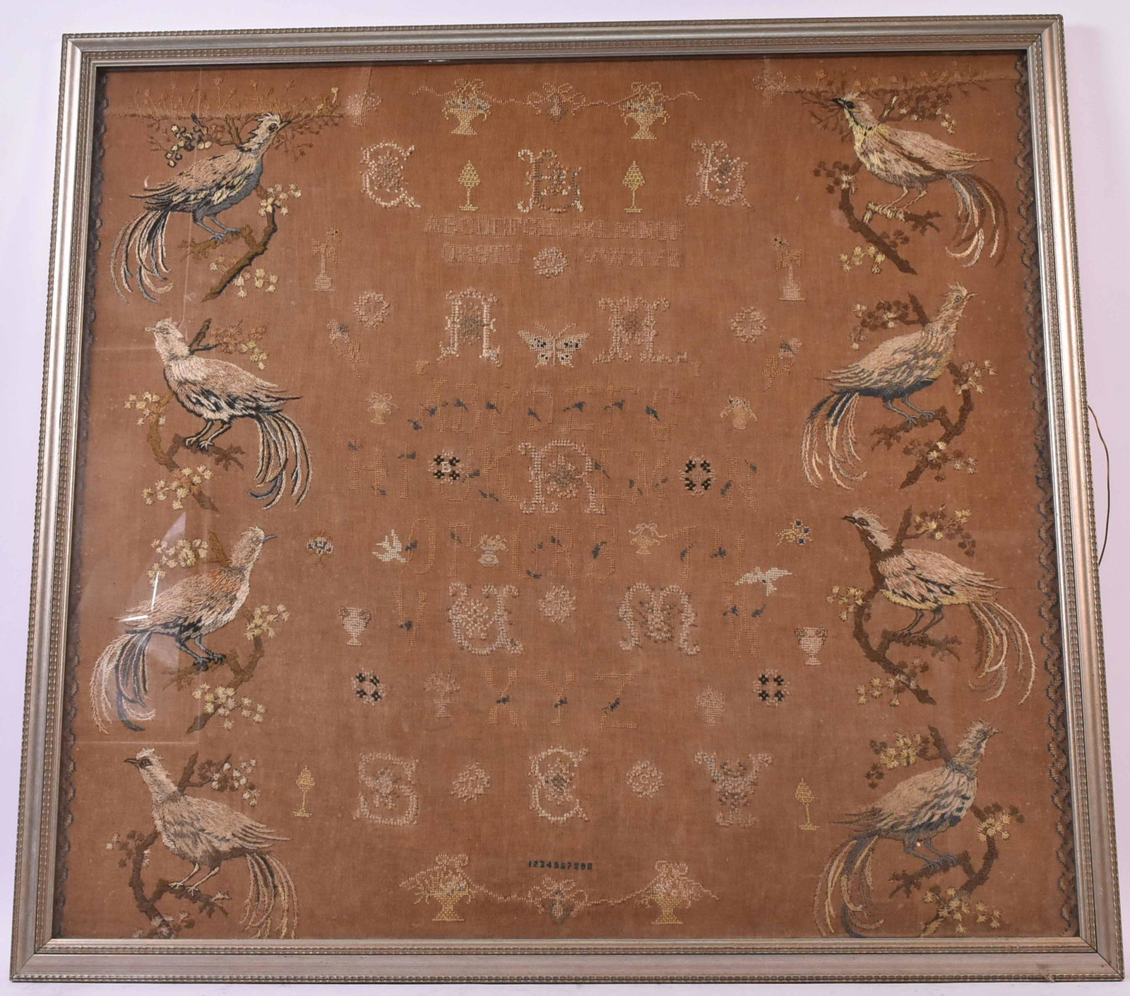 Needlework Sampler New York Ella Rumsey: American, 19th Century. The borders decorated with pheasants flanking a cross stitched later alphabet. Size: 34 1/2"h x 38"w Provenance: Property from the Estate of Judith Applegate, Princeton, NJ.