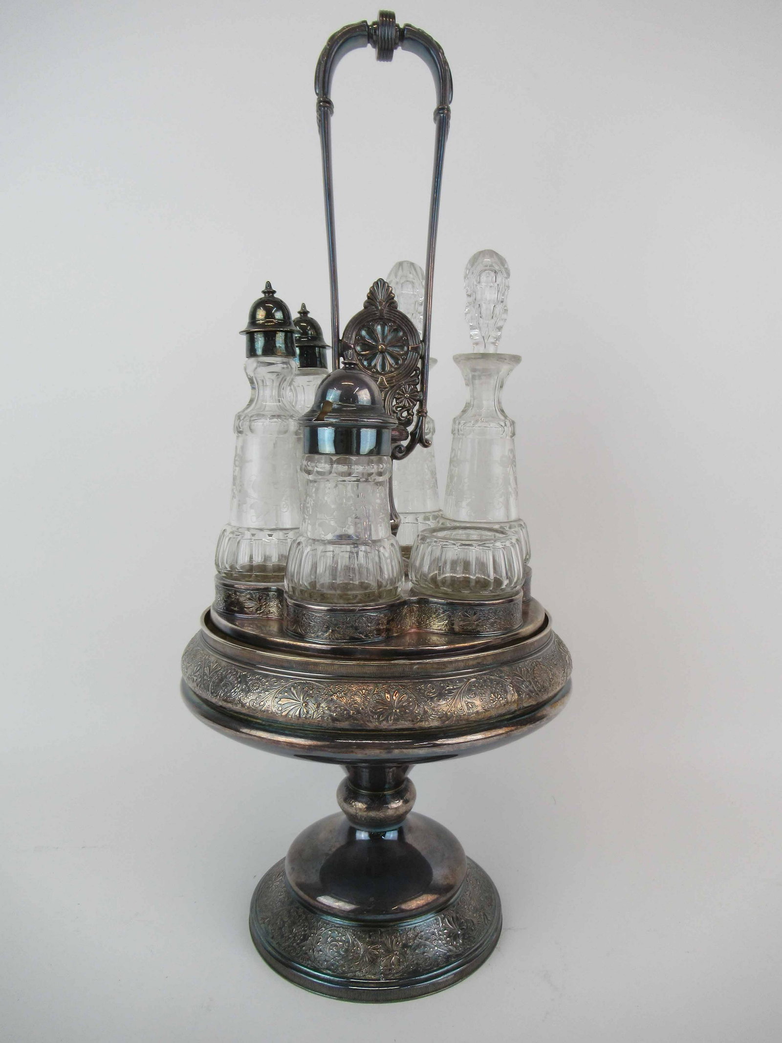 Victorian Middletown Silver Plate Caster Set: Victorian Middletown Silver Plate Caster Set. Having six vessels with etched glass vines and bows. Used condition, minor chips to stoppers. 19 1/4" tall x 9" diameter.