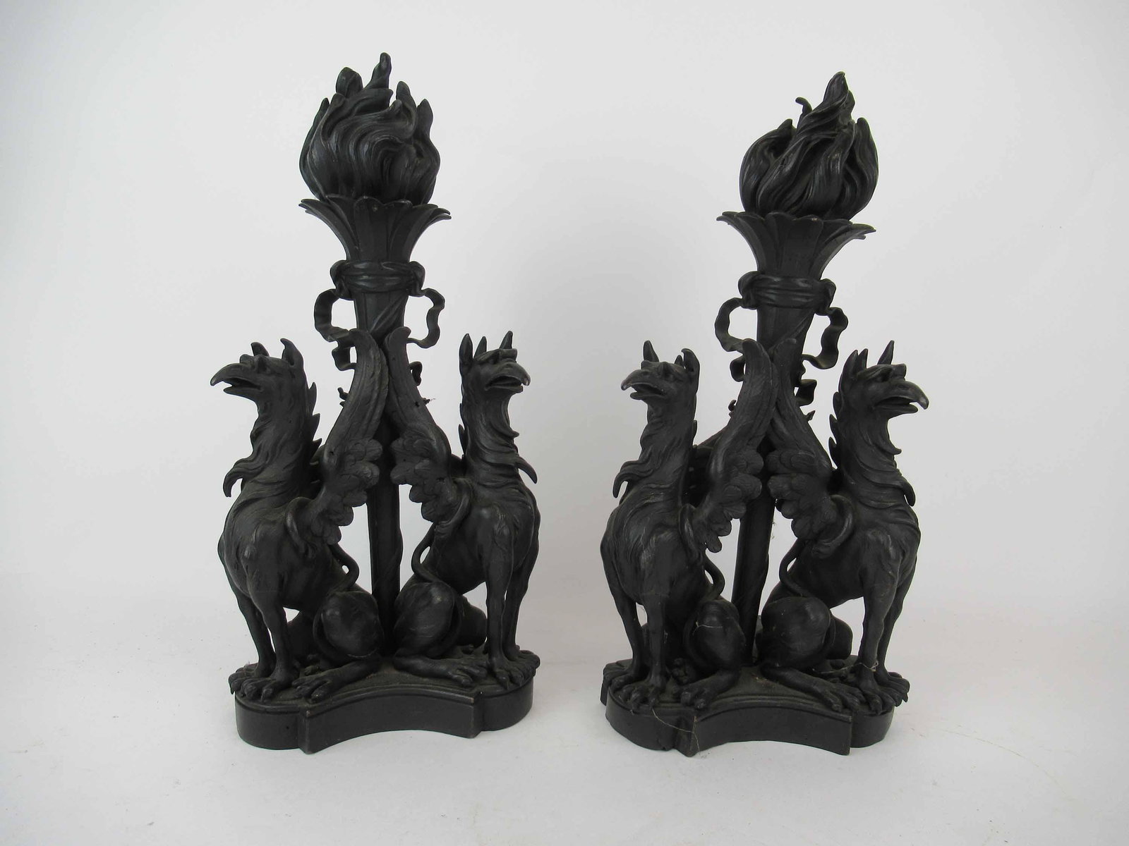 Pair of Antique Bronze Winged Griffin Andirons: Pair of Antique Bronze Winged Griffin Andirons. Each having two winged Griffins with a central torch flame. Used condition, wear, worn, broken wings. 15 1/4" tall x 7 1/2" x 6 1/2" deep