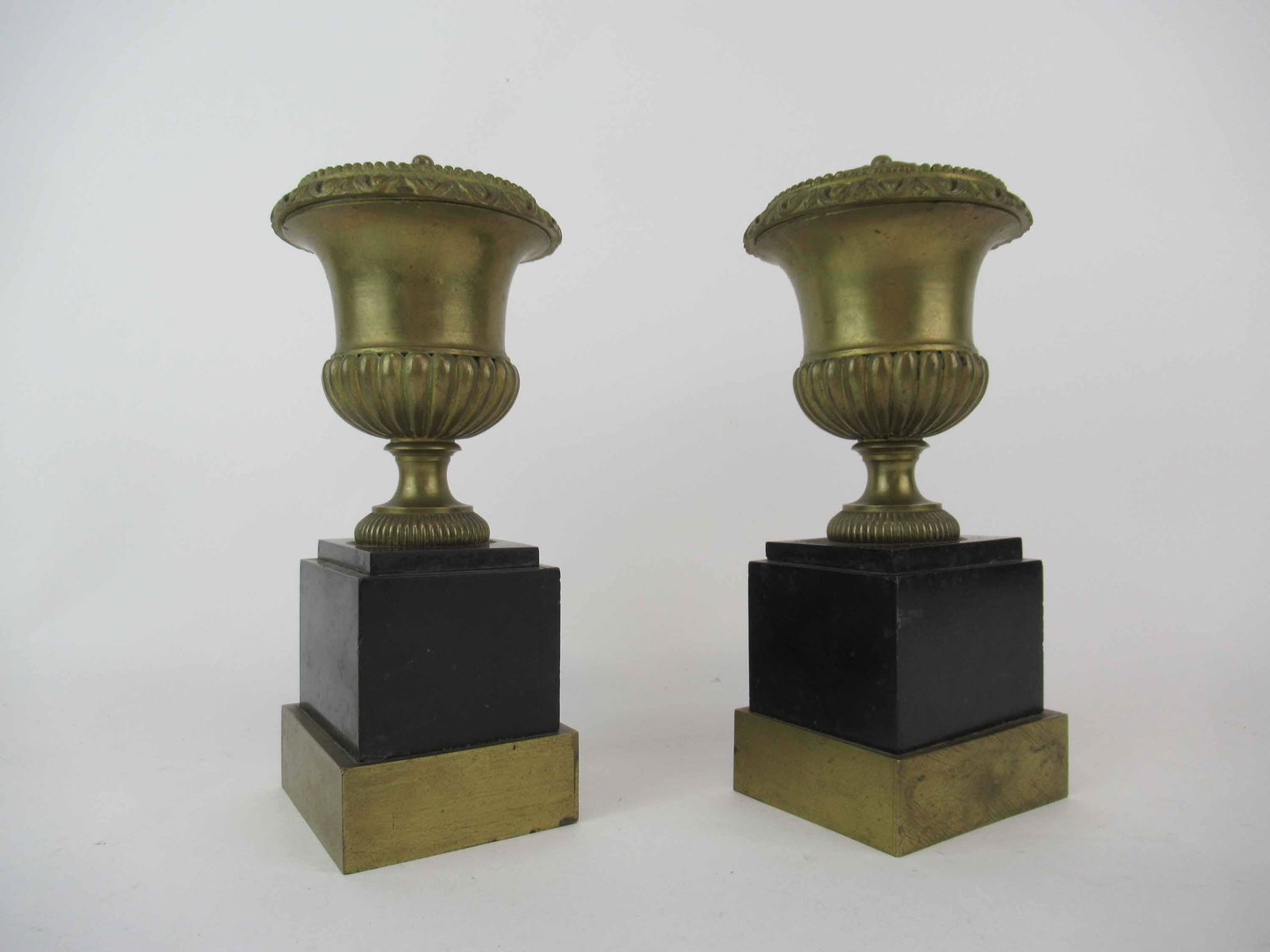 Pair of Bronze Lidded Urns: Pair of Bronze Lidded Urns mounted on black granite base with greek key and leaf design; used condition, wear/worn minor chips, crack/repair to side, measures 9" high x 3 3/4" long x 3 1/8" wide