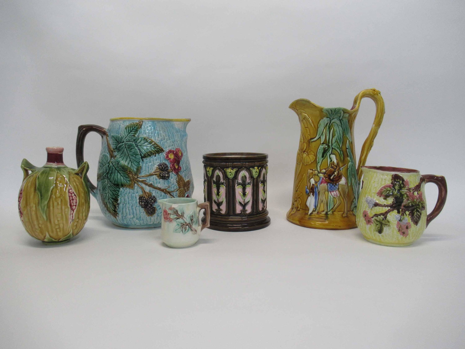 Group of Assorted Majolica Table Articles: Group of Assorted Majolica Table Articles. Including blackberry and leaf pitcher, Arabian night pitcher with repair to spout and hairlines, berry and leaf creamer with chip to rim, tobacco jar missing