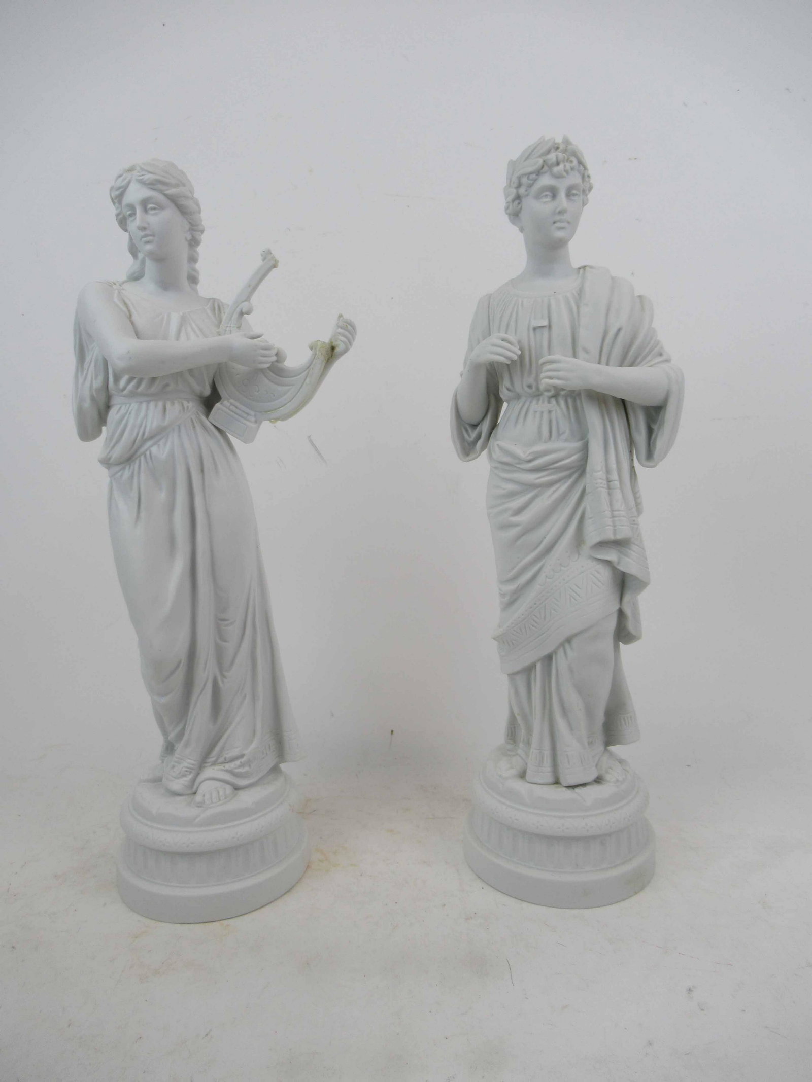 Pair of Porcelain Bisque Neoclassical Figures: Pair of Porcelain Bisque Neoclassical Figures. Depicting Man and Woman playing broken harp. Used condition, breaks, both missing pieces. Tallest 17 1/4"