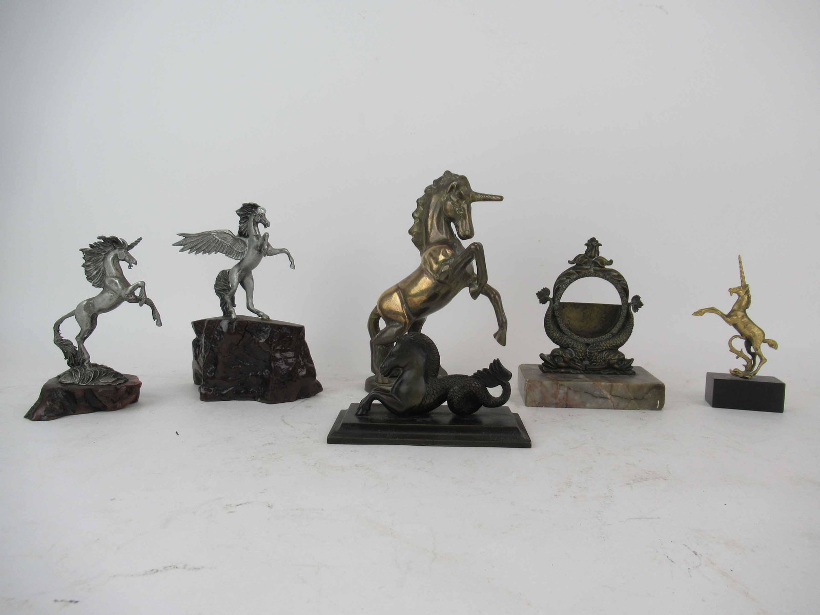 Bronze Seahorse Hippocampus Figural: Bronze Seahorse Hippocampus Figural. Together with bronze dolphin form frame, brass unicorn, brass unicorn with dolphin and two wood mounted horses. Largest unicorn 7 3/4" tall x 5 1/2" wide.