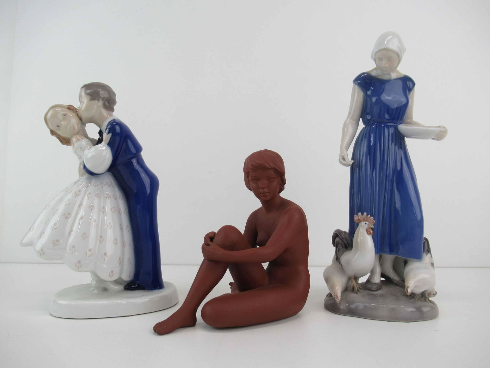 Two B & G Bing and Grondahl Porcelain Figurines: Two B & G Bing and Grondahl Porcelain Figurines including Youthful Boldness #2162 and Poultry Girl #2220 depicting a girl feeding chickens together with a Goebel terracotta sitting female nude. Used c