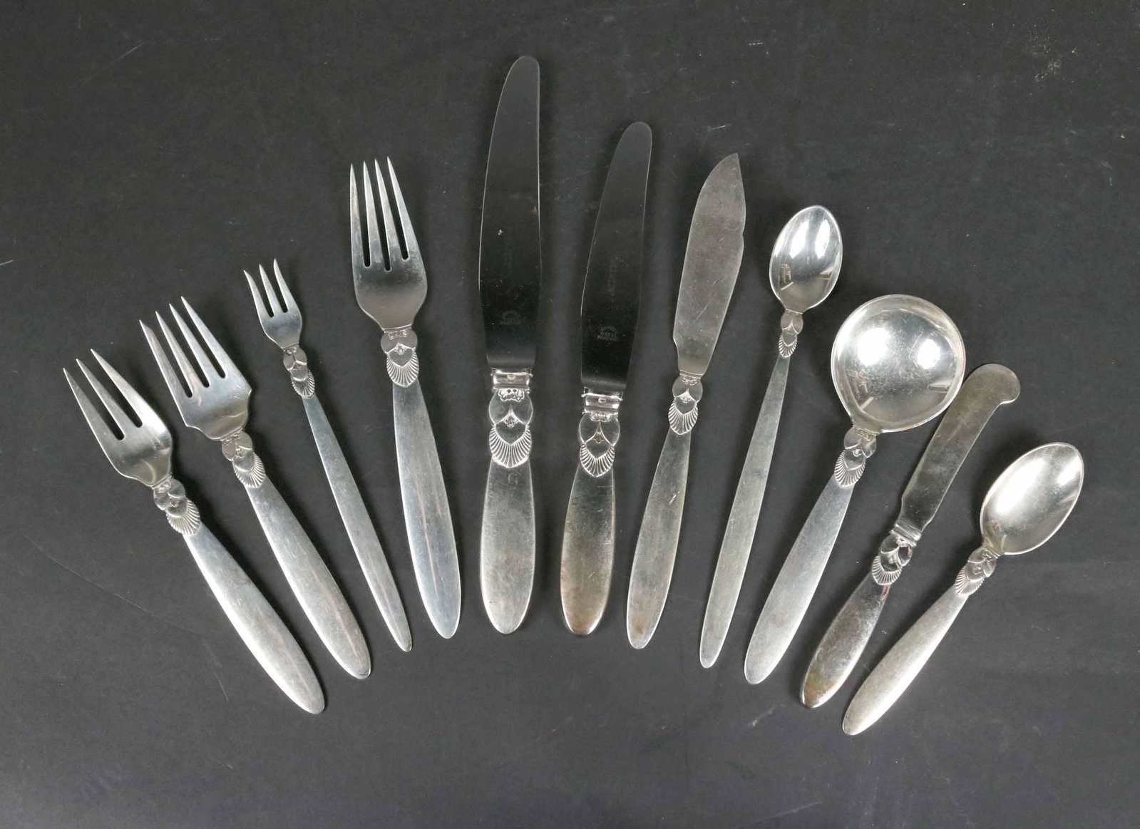 Georg Jensen Sterling "Cactus" Pattern Flatware: Comprising: Twelve dinner forks and knives, (One dinner fork has a sharp blemish on it's back bowl as shown in the photos.) ( a second fork has two sharp dents on the back of the handle not visible fr