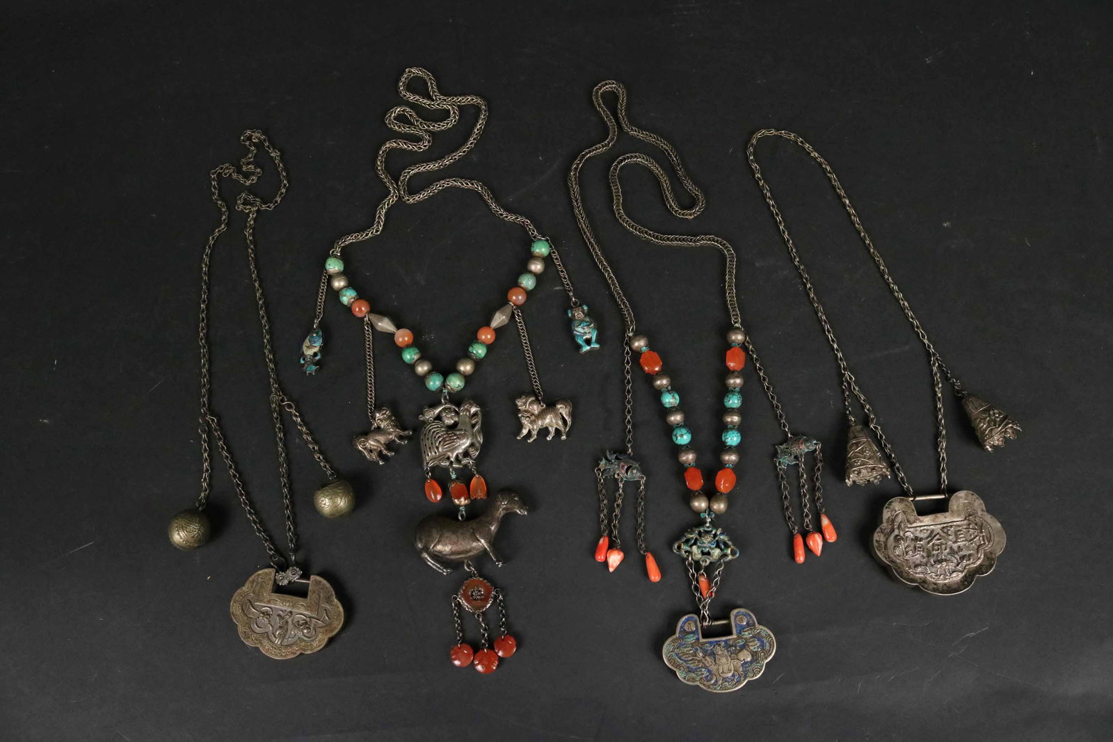 Chinese Silver Necklace with Goat and Foo Dogs: Together with three Chinese silver necklaces. The first, with a colored medallion, hard stones and fish pendants, the last two with medallions and bells. 24"l