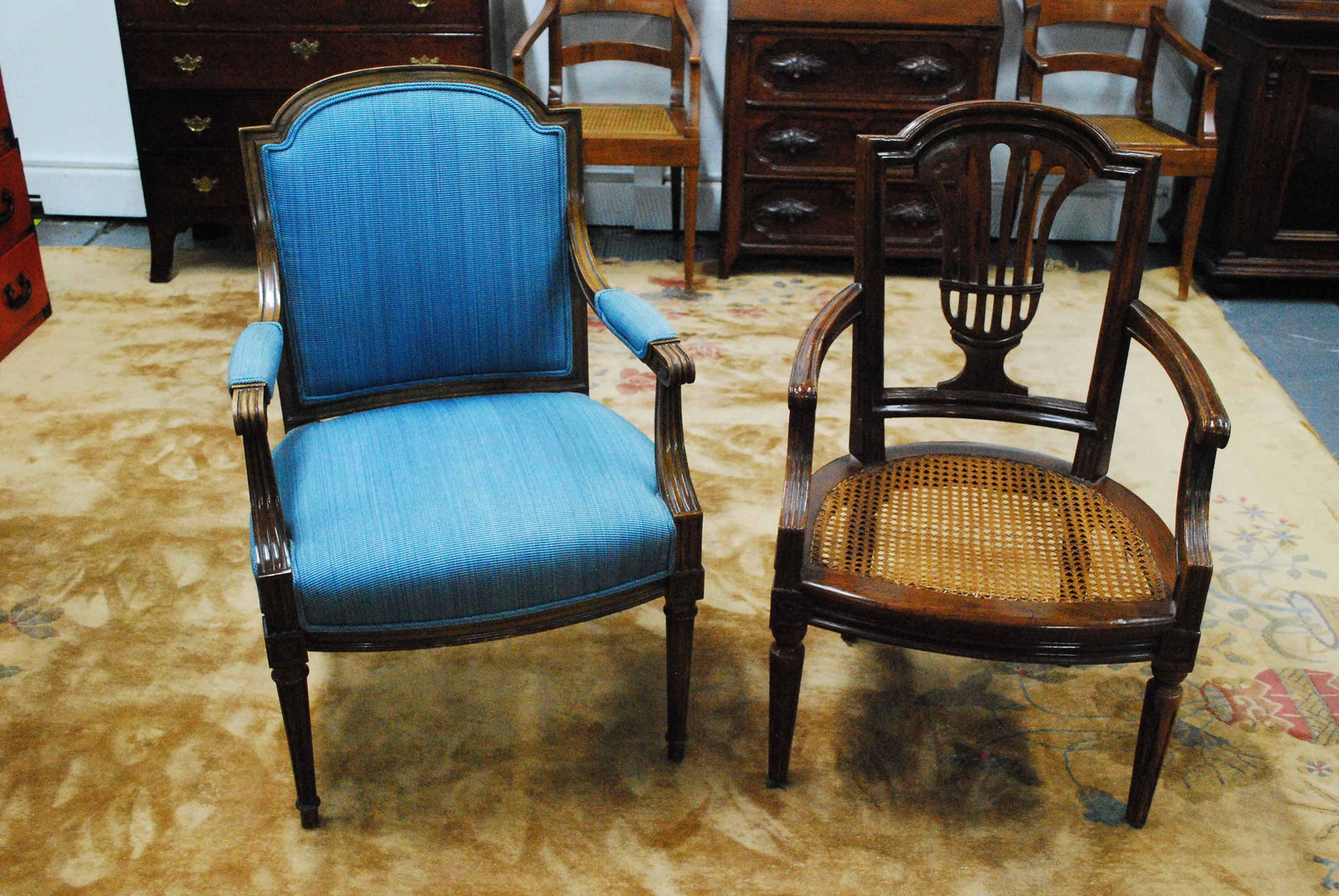 Two Louis XVI Style Armchairs: Two Louis XVI Style Arm Chairs having complementary designs with carved rosettes, one has a carved back with cane seat and seat cushion marked Italy, the other has blue upholstered seat, back and arms