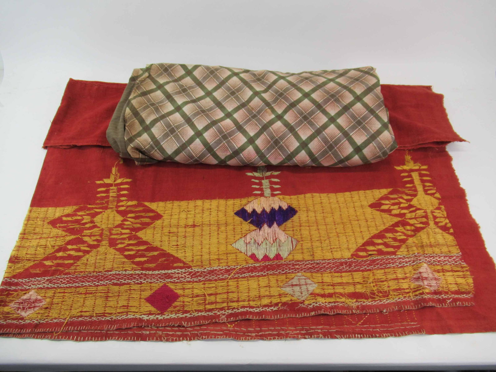 Ikat Bedcover: Ikat Bedcover having red, pink, white and yellow coloring with a patchwork backing, together with a rust colored embroidered linen pieced textile. Used condition, wear/worn, stains, tears, losses, Ika