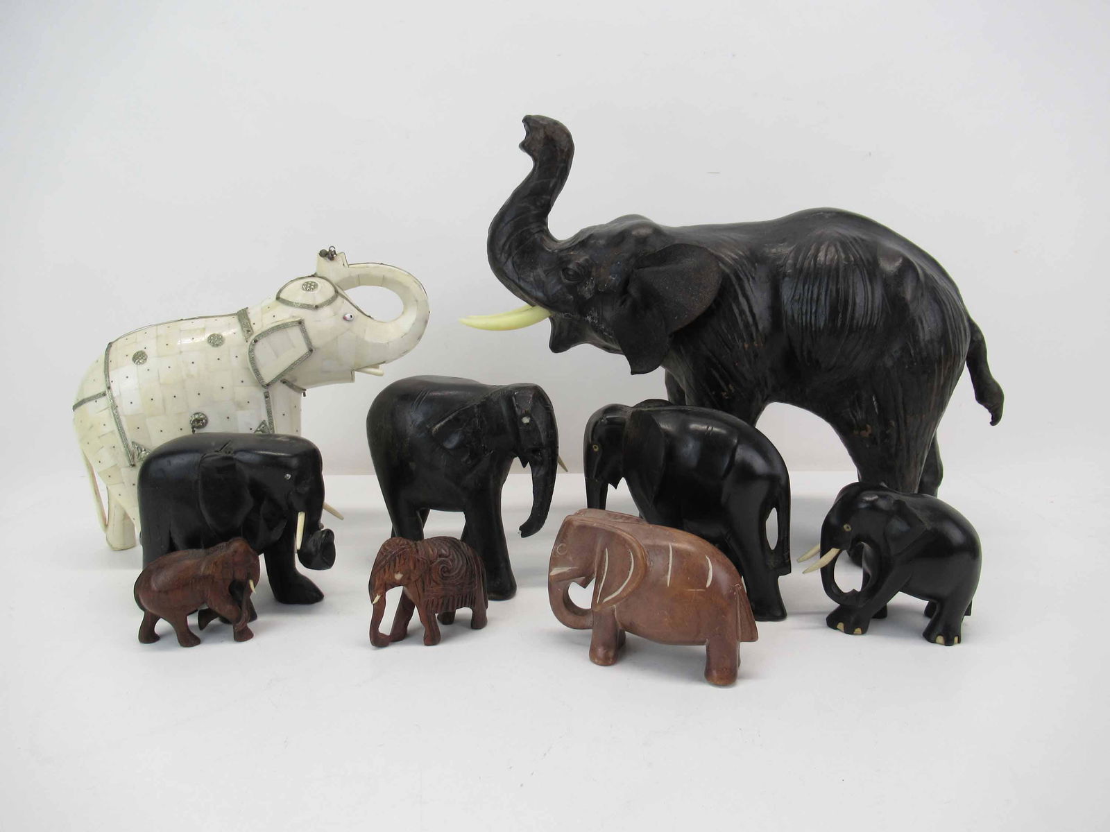 Group of Assorted Elephant Figures: Group of Assorted Elephant Figures comprising of a leather elephant, a bone inlay Asian elephant, four carved ebony wood elephants, two small carved wood elephants and a stone carved elephant; used co