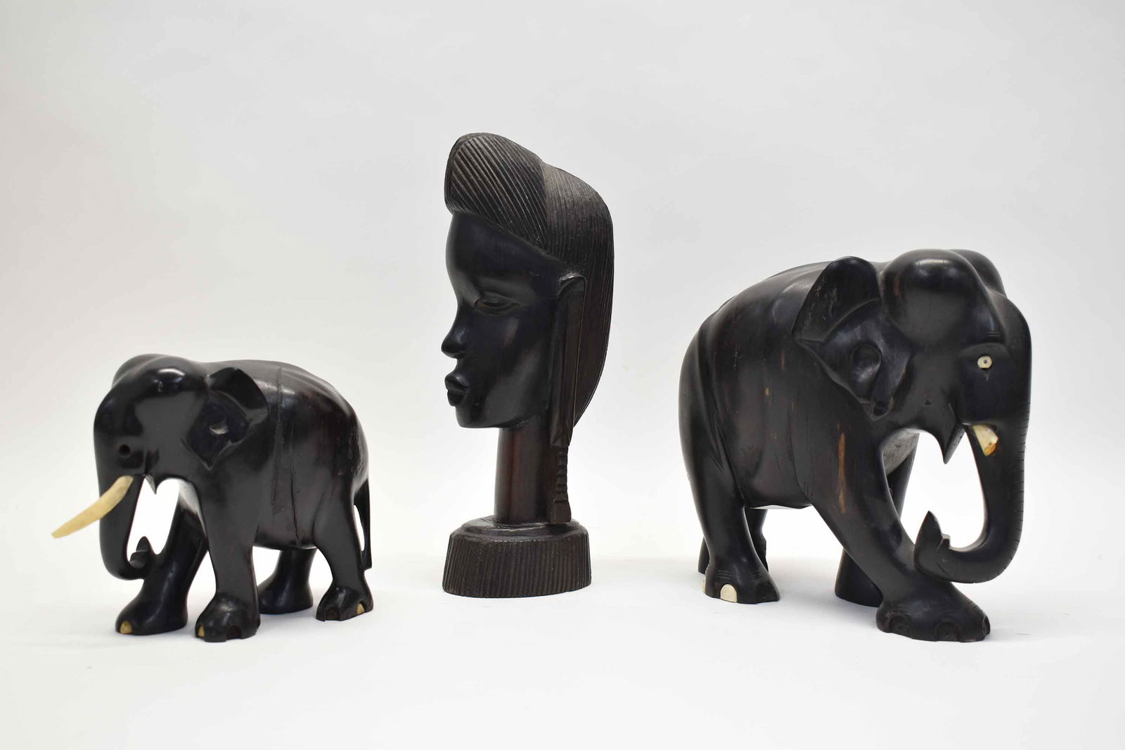 Group of Ebony Wood Carvings: Group of Ebony Wood Carvings including two African Elephants and one carved bust; used condition, wear/worn, scratches, losses to elephants, splits and breaks to wood, largest measures 6 7/8" high x 7