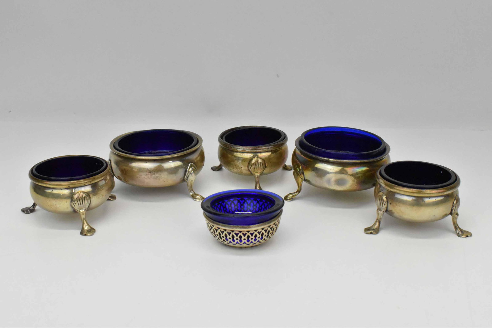 Group of Sterling Salt Cellars: Group of Sterling Salt Cellars with cobalt liners, larger two are marked Frank M Whiting Co. George II, smaller 3 footed are marked B & M Sterling 43 and pierced salt has Webster hallmark; used condit