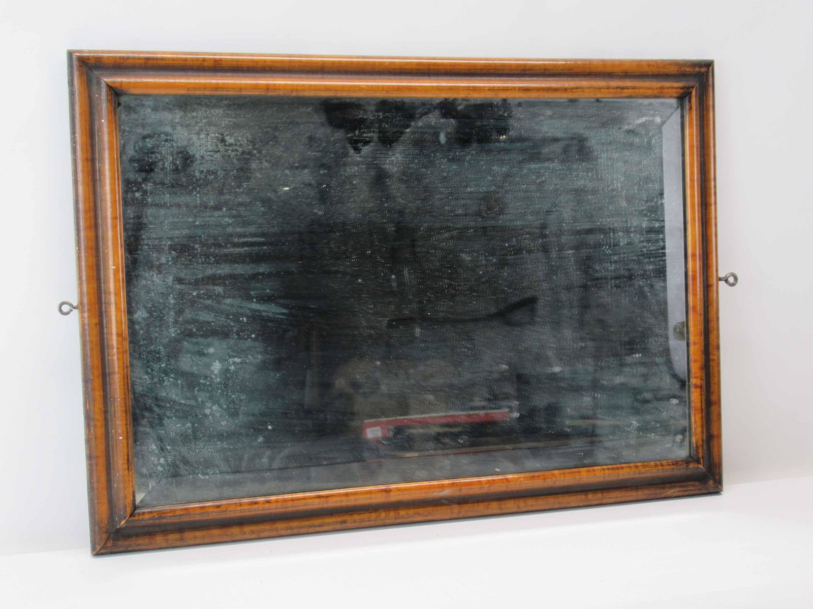 Antique Beveled Mirror in Maple Frame: Antique Beveled Mirror in Maple Frame. Used condition, wear, worn, having a loop screw on two sides. Frame size 14 1/4" x 20 1/8". This is one of many Select items from an office at the Empire State B