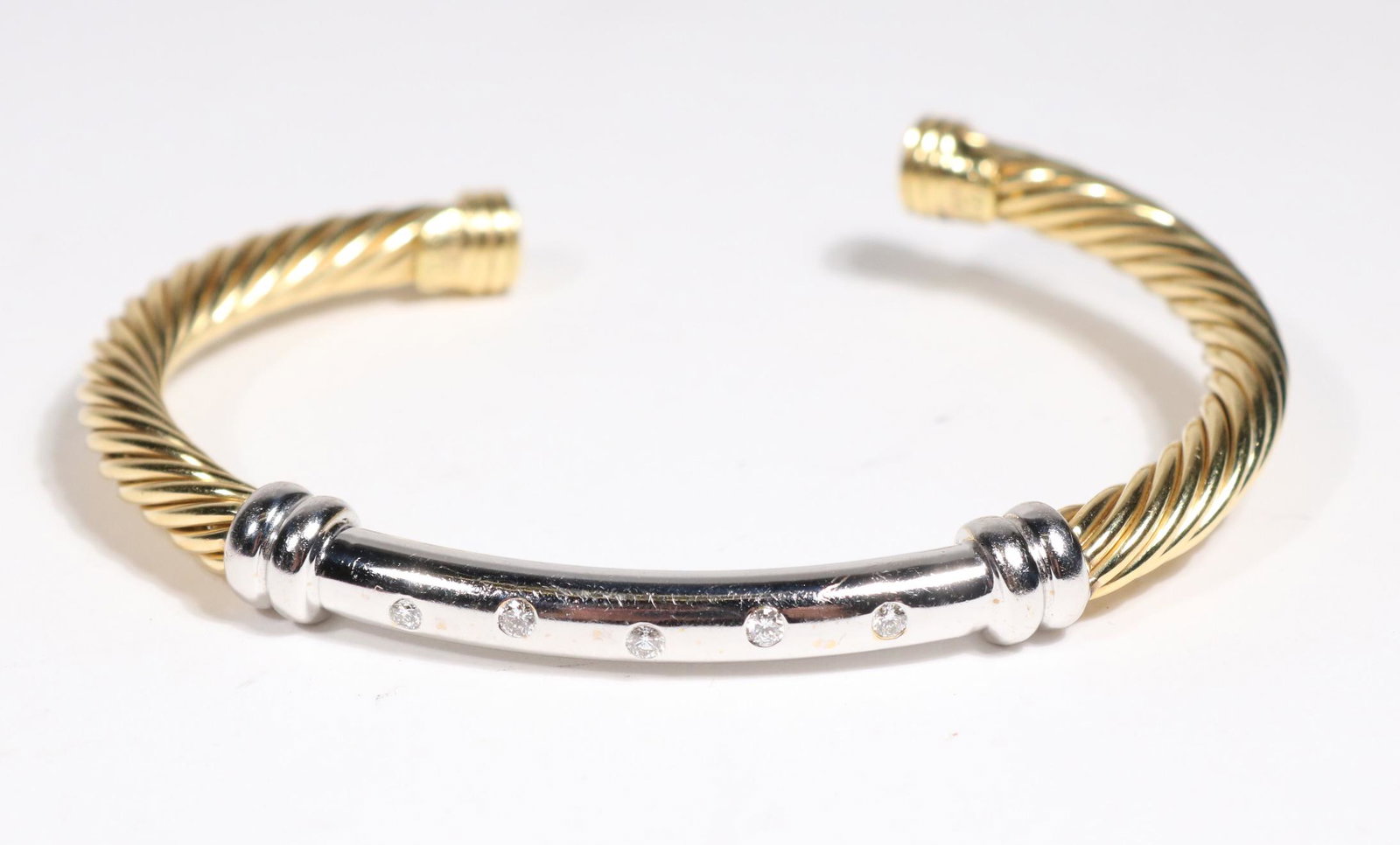 David Yurman Yellow Gold and Diamond Cable Cuff: A YELLOW GOLD CABLE CUFF WITH WHITE GOLD CENTER BAR WITH DIAMONDS, BY DAVID YURMAN in 18k yellow gold METAL: 18 Karat yellow gold STONES: 5 diamonds weighing approximately 0.25 carats total SIGNATURE:
