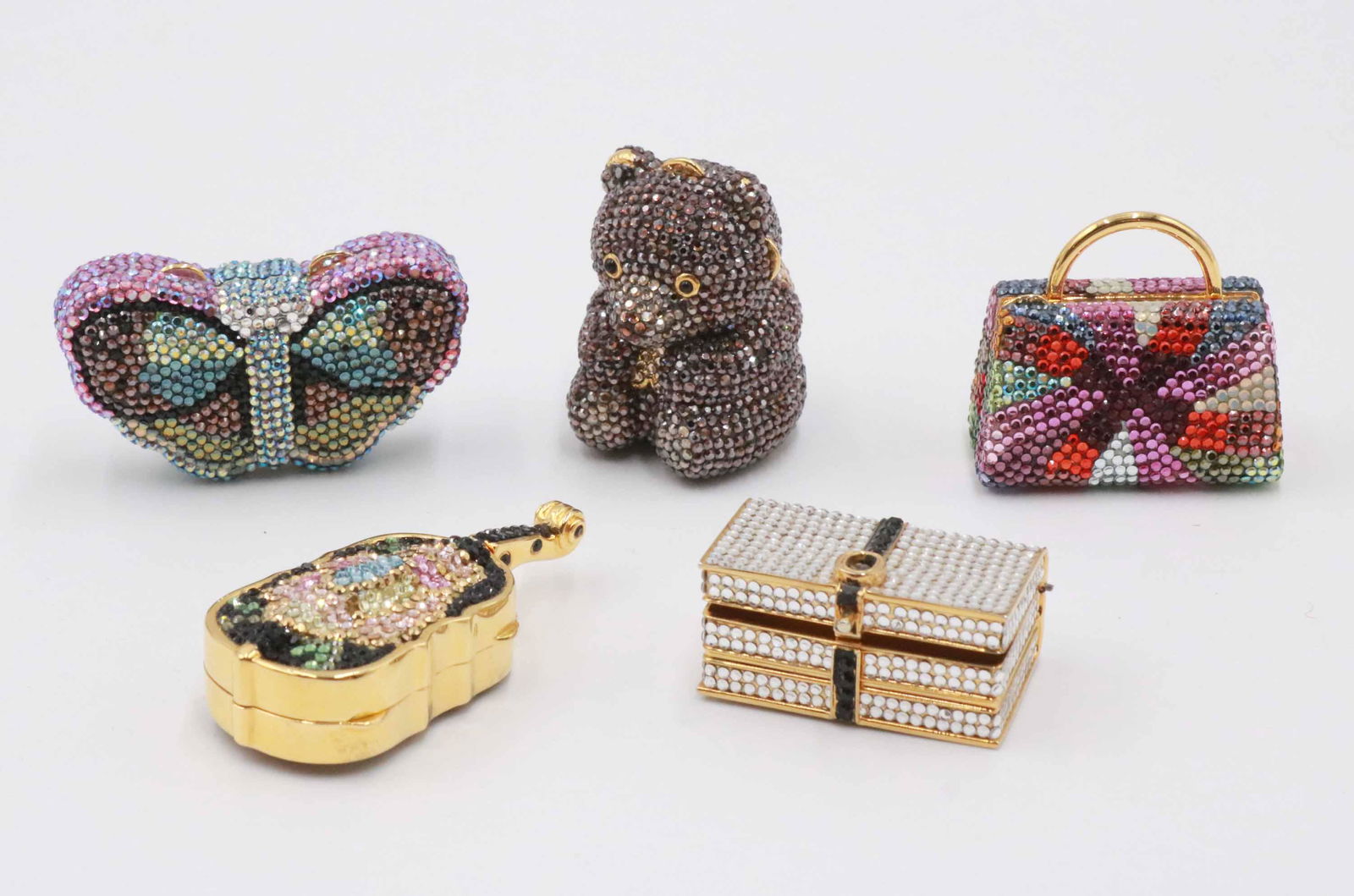 Four Judith Leiber Crystal Pillboxes: Comprising: a violin with a Nieman Marcus tag, a butterfly box, a teddy bear form box, and an handbag form pill box. Each marked Judith Leiber. Together with a crystal decorated box form pill box whic