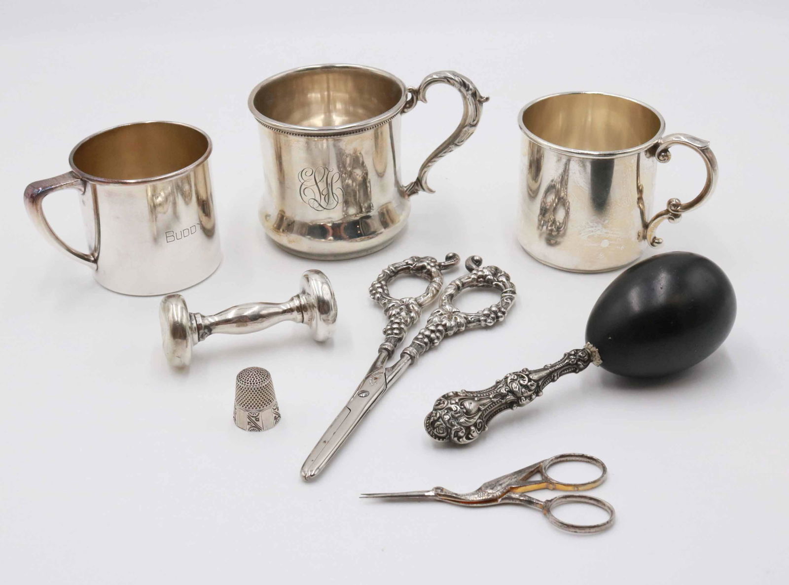 Two Sterling Silver Baby Cups: Apx. 6 t.o. Together with a silver plated baby cup, an unmarked silver rattle, #10 silver thimble, a darning sock egg with sterling handle, grape shears, and a crane form scissors. Monograms and dings