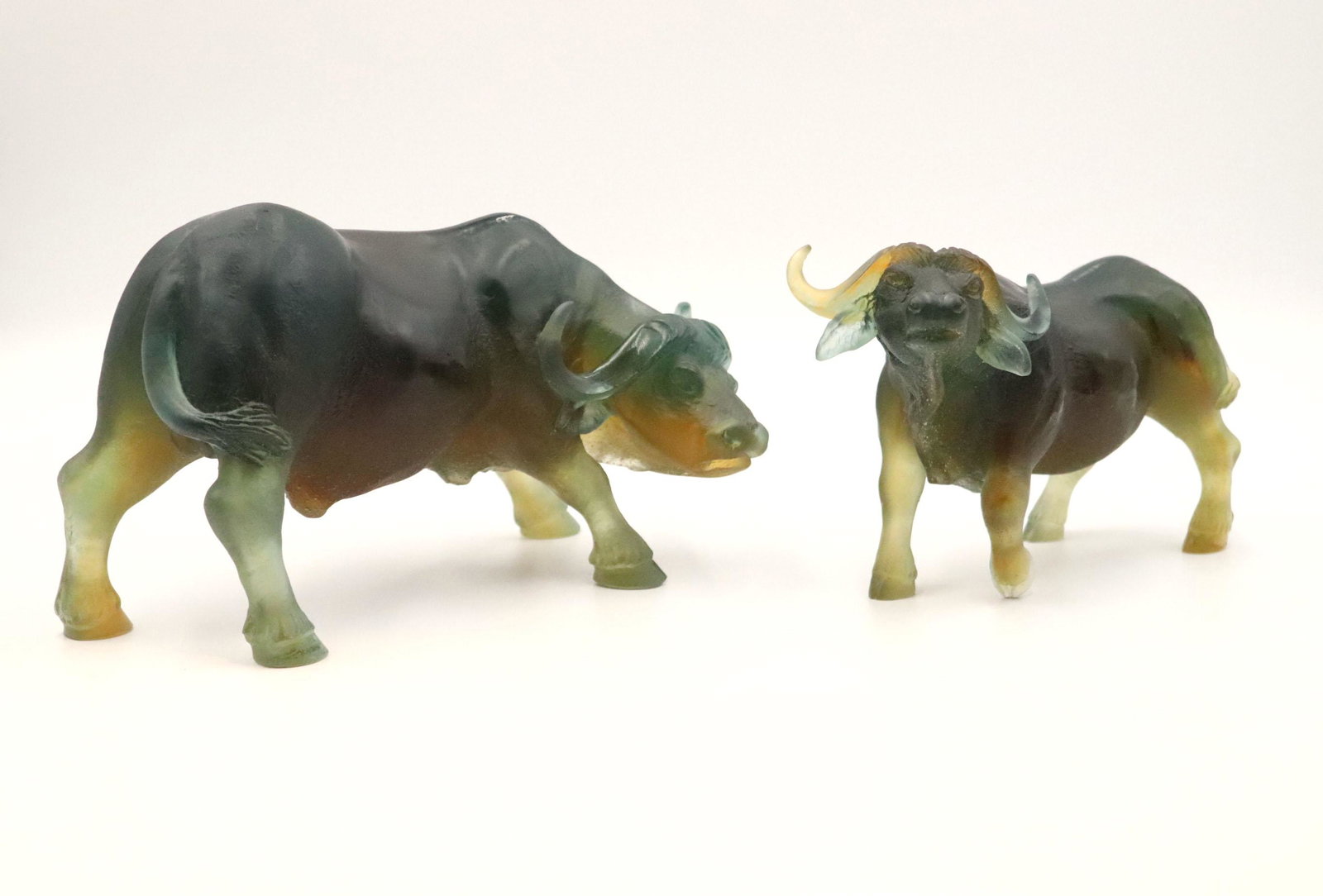 Two Daum Pate de Verre Water Buffalo Sculptures: Both signed underside, one with head raised and one with head bowed. 5-1/2"h x 8-1/2"w and 6"h x 11"w Property from a Short Hills, NJ and San Francisco, CA Private Collection