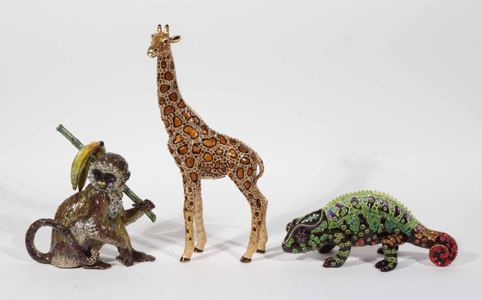 Three Jay Strongwater Animal Figurines: Comprising, a monkey with bananas, a giraffe, and a gecko. Giraffe: 7-3/4"h Gecko: 2-1/2"h x 5-1/2"w Monkey: 4-1/2"h x 4-1/2"w Property from a Short Hills, NJ and San Francisco, CA Private Collection