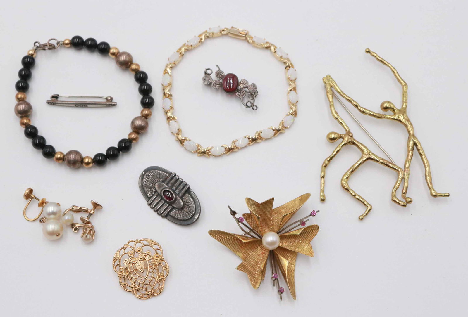 Group of Ladies Jewelry: Including a 14K yellow gold and synthetic opal link bracelet, 7"l, gold plated modernist dancing couple pin, 3-1/4"h, black, gold beaded bracelet, and three pins.