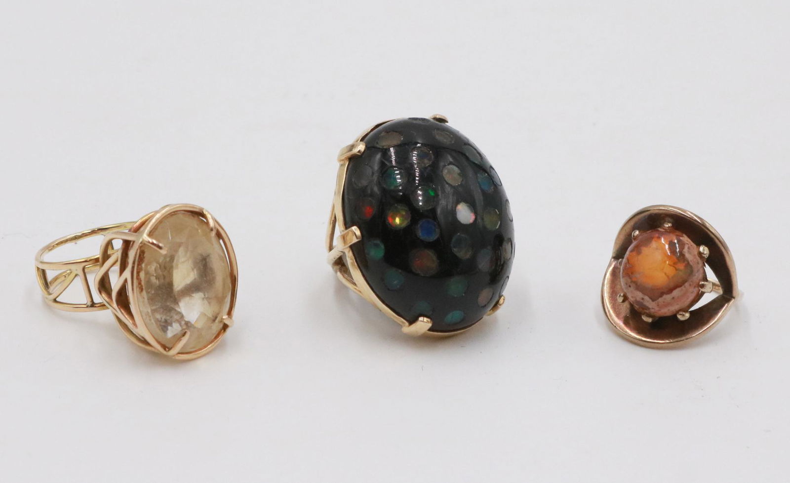 Three Yellow Gold and Gemstone Rings: All apparently unmarked, comprising one set with an oval faceted lemon quartz, approx. 13ct, one large oval black hard stone, third possible amber, all ring size approx. 6.