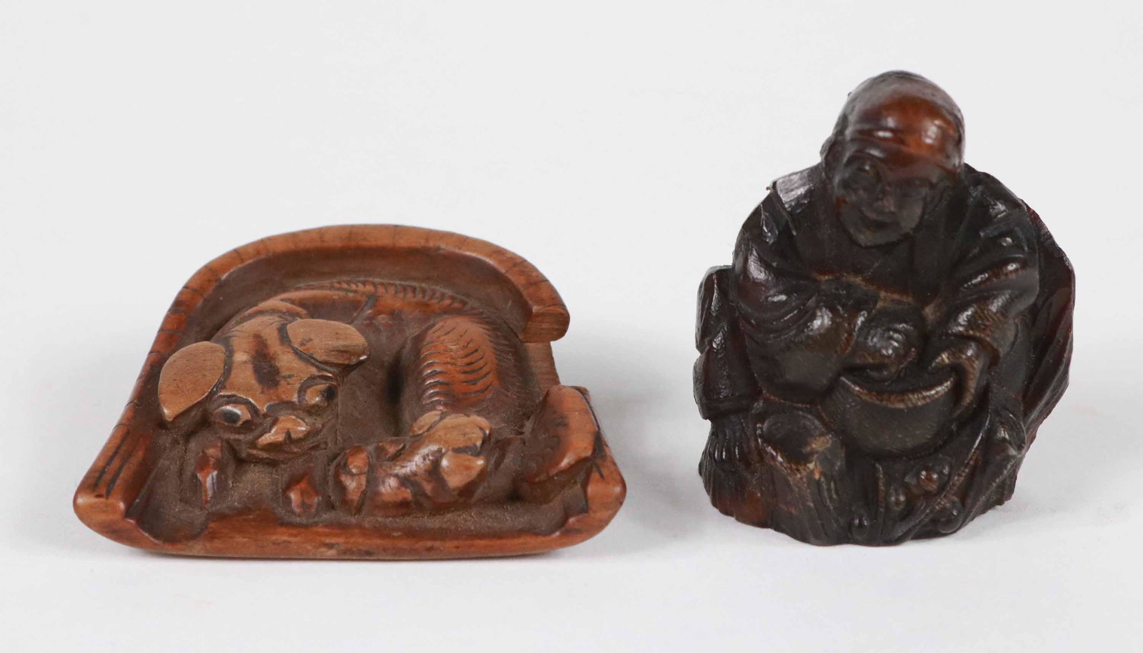 Two Carved Wood Netsukes: Chinese, one of seated man and one of fu dog laying down. 1-1/2"h