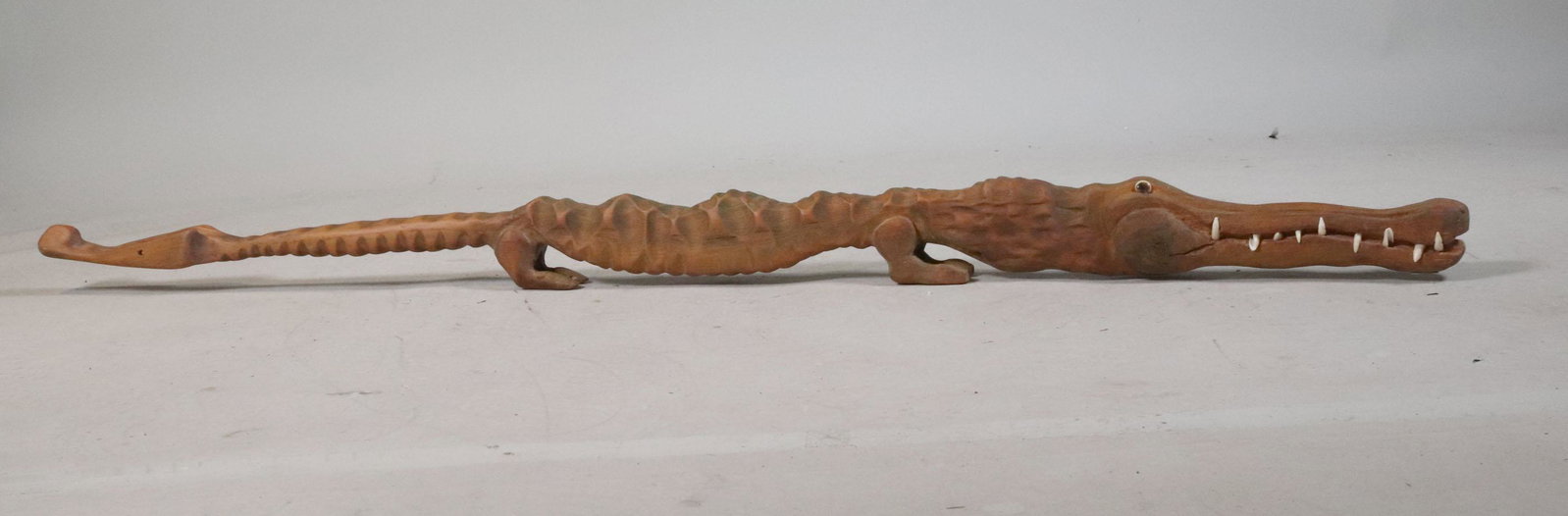 Folk Carved Gator Wash Tub Bass Pole: American, 20th C. mounted with teeth. Apx. 60"l Provenance: Property from the Steve and Stephanie Alpert Collection