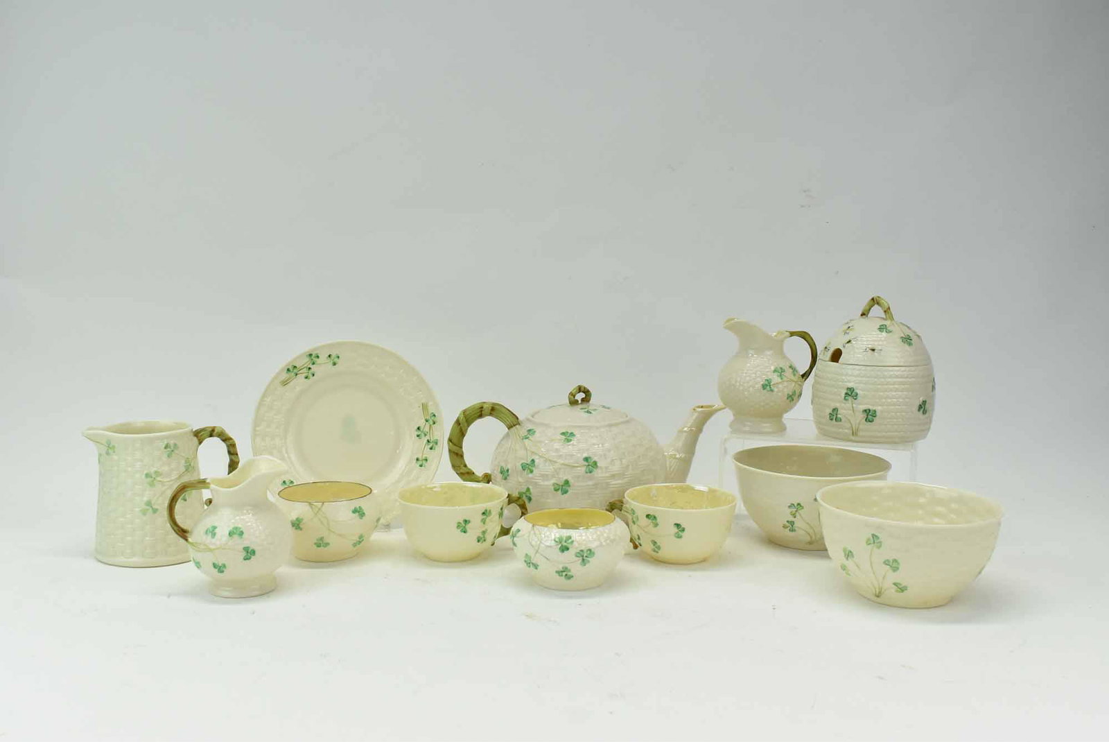 A Group of Belleek Shamrock Pottery: A Group of Belleek Shamrock Pottery, 12 pieces in total, including teapot, cups, honeypot, creamers and more; used condition, wear/worn, teapot measures 10” handle to spout x 6” wide