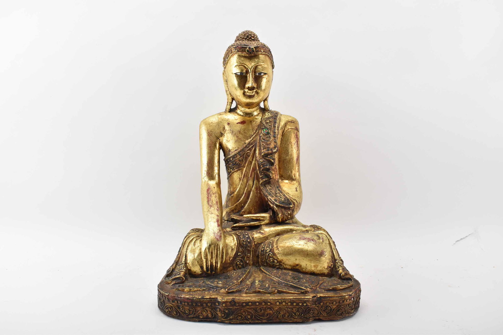 Carved Giltwood Buddha Statue: Carved Gilt Wood Buddha Statue, in a lotus position; used condition, wear/worn, cracks and splits to wood, split and repair to midsection of body, paint loss, measures 16 3/4" high x 12" wide x 9"
