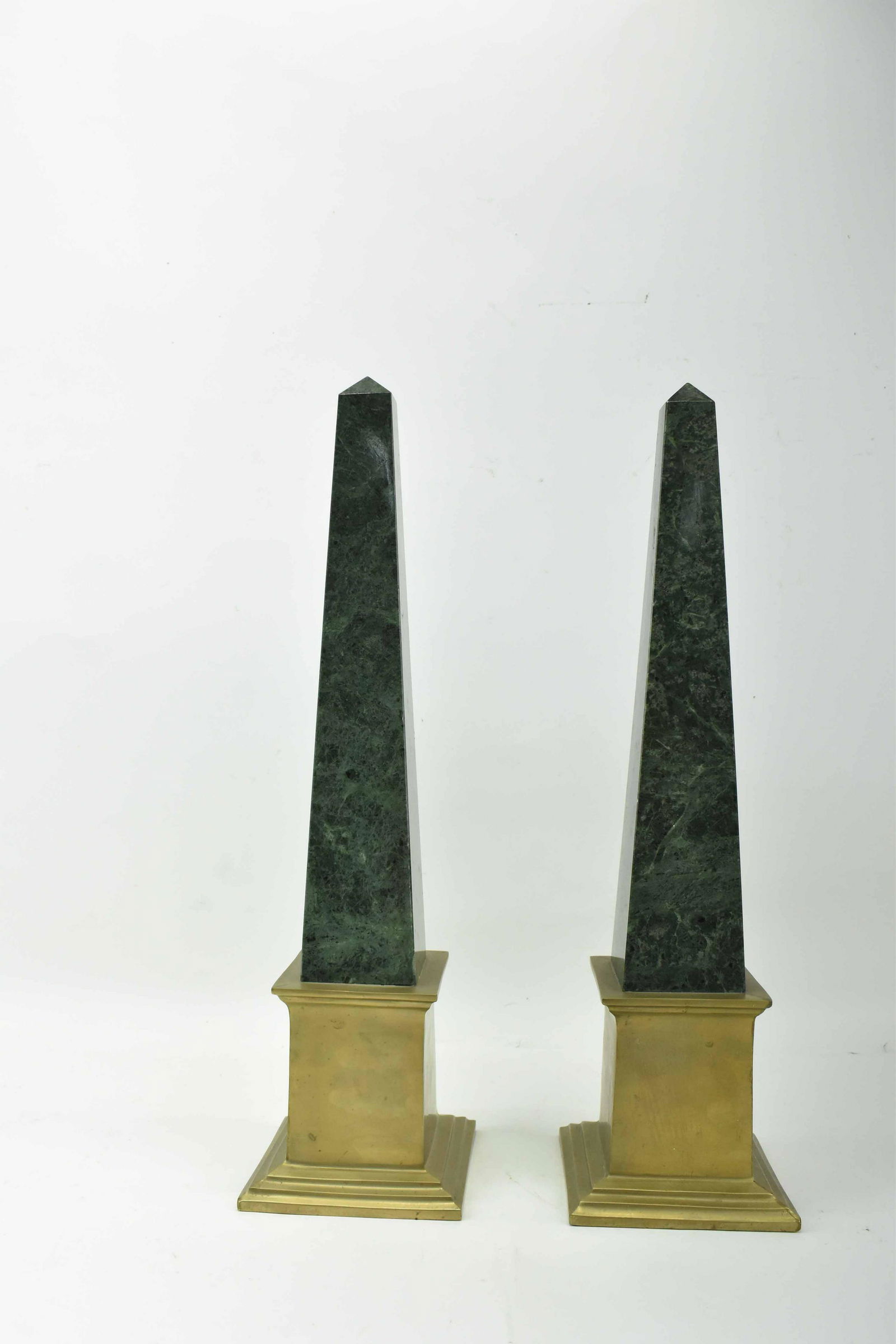 Pair of Granite Obelisks: Pair of Granite Obelisks mounted on brass plinths, green in color; used condition, wear/worn, chips, scratching, measures 21 1/4" tall x 5 3/4" x 5 3/4"