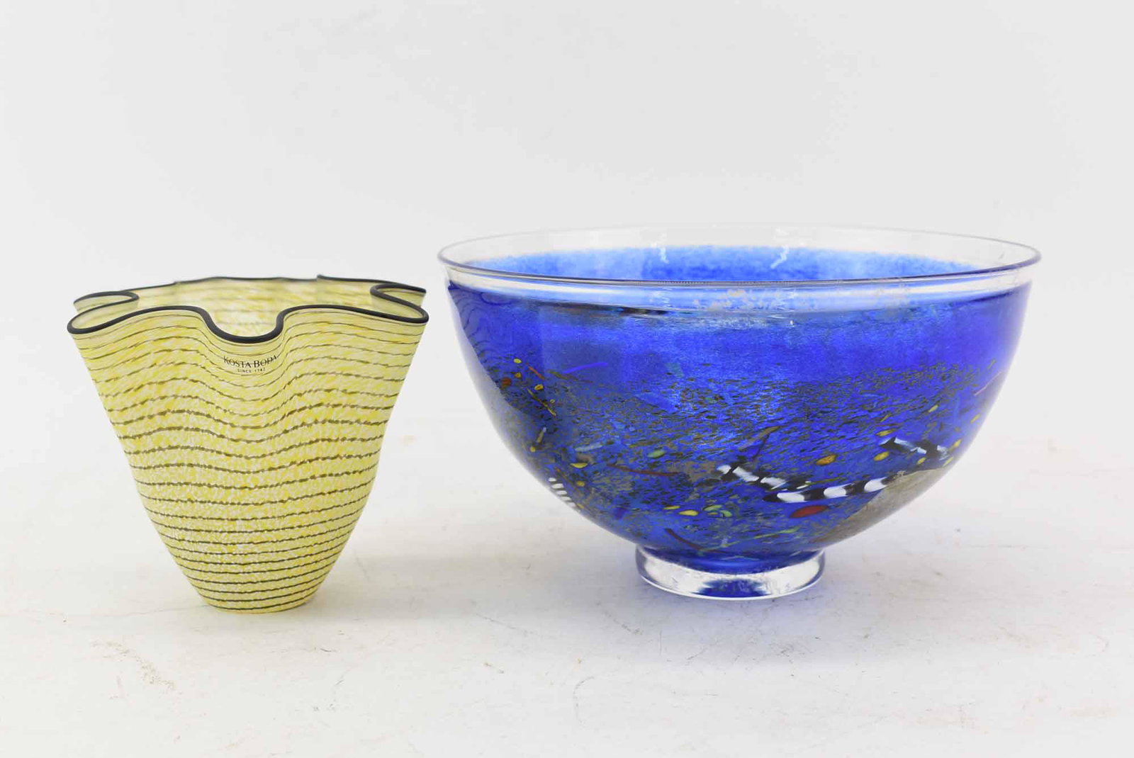2 Kosta Boda Art Glass Bowls Signed: 2 Kosta Boda Art Glass Bowls Signed, both with stickers, one cobalt signed Kosta Boda B. Vallien, the other yellow stripe with ruffle edge signed Kosta Boda Ulrica HV; used condition, wear/worn, scrat