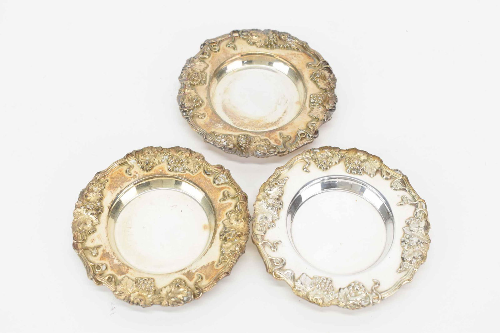 Three Silver Plated Wine Coasters: Three silver plated wine coaster, grape & vine border motif, each 4-3/4"d, used.