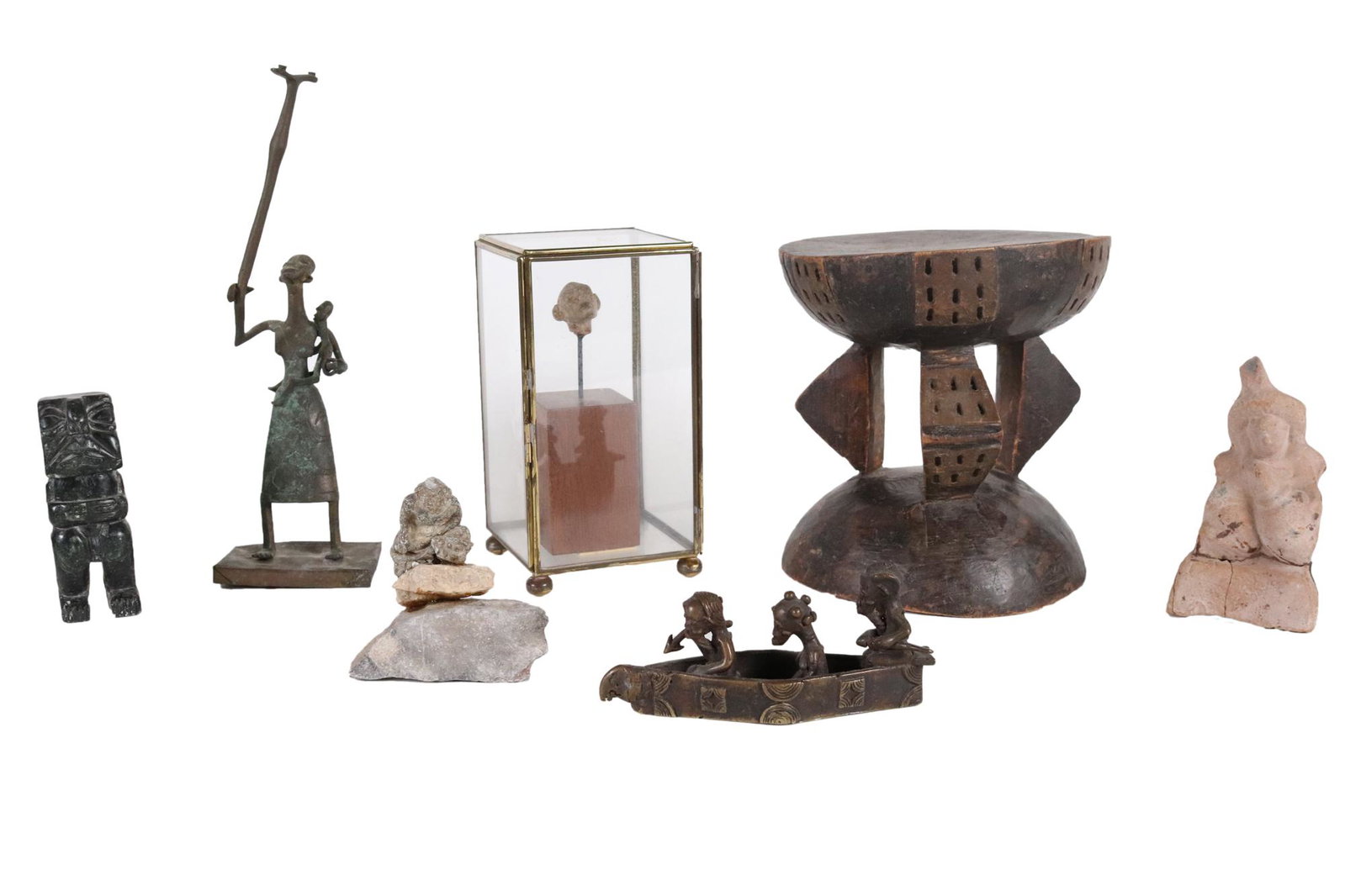 Group of Decorative and Ceremonial Objects: Including a small bronze of three figures in a boat, a carved stone head, a seated terracotta figure, and others, 7 pieces total Provenance: Property from the Estates of David and Laura Finn, Westches