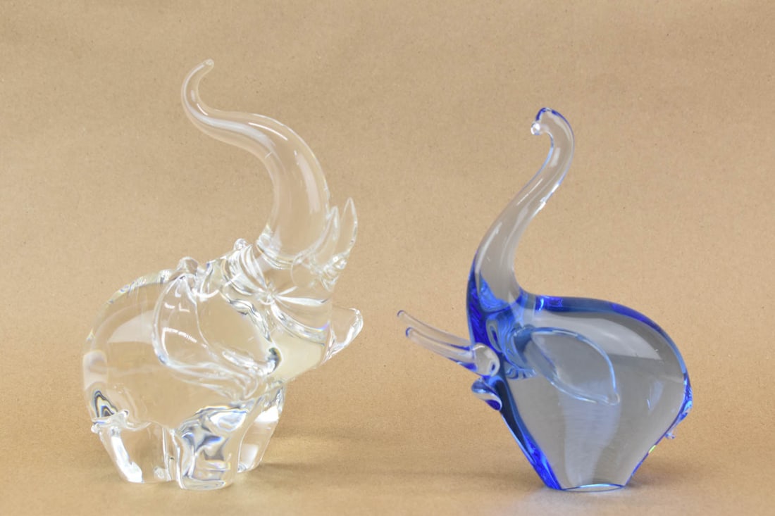 Two Art Glass Elephant Sculptures: Two Art Glass Elephant Sculptures, one blue and the other colorless. Both trunks up and appear to be in good condition, free from chips and cracks. There appears to be a made in the making rough spot 