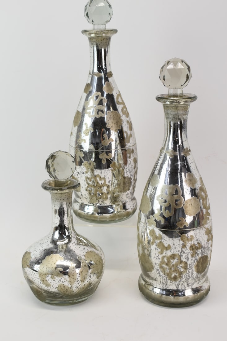 Set of 3 Mercury Glass Decanters: Set of 3 Mercury Glass Decanters having a floral decoration cut into outside of glass, comprising a pair of tall decanters and a shorter decanter of varying shape; used condition; largest decanters me