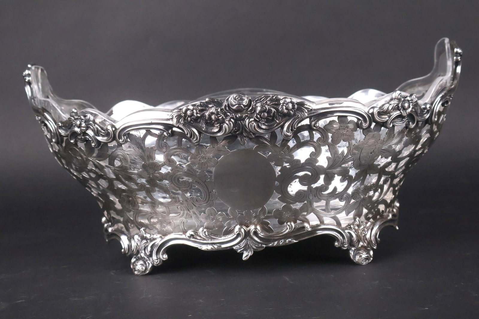 Large 19th C. English Sterling Reticulated Center Bowl: The floral decorated bowl with glass insert (crack to glass). Marks: Sterling, London, Daniel and John Wellby, 1896. 6.5"h x 15"l x 11.5"d and approx. 67 t.o. without the glass insert.