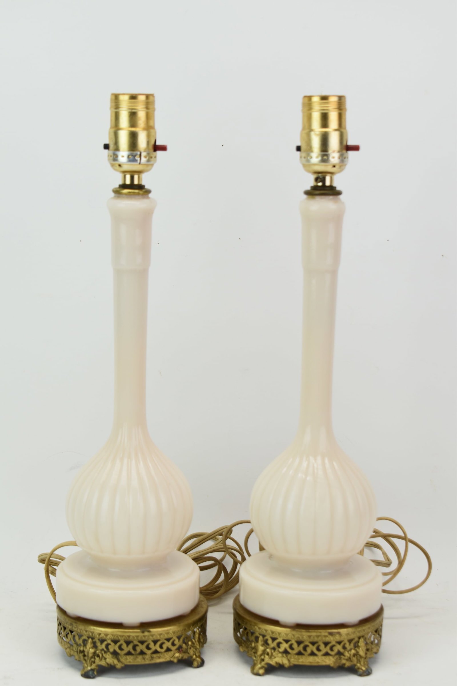 Pair of Vintage ivory Tone Milk Glass Lamps: Pair of Vintage ivory Tone Milk Glass Lamps Pair of Vintage Ivory Tone Milk Glass/Opaque Glass Lamps mounted on ornate gilt metal round bases; used condition, some losses/tarnish to gilt; each measure