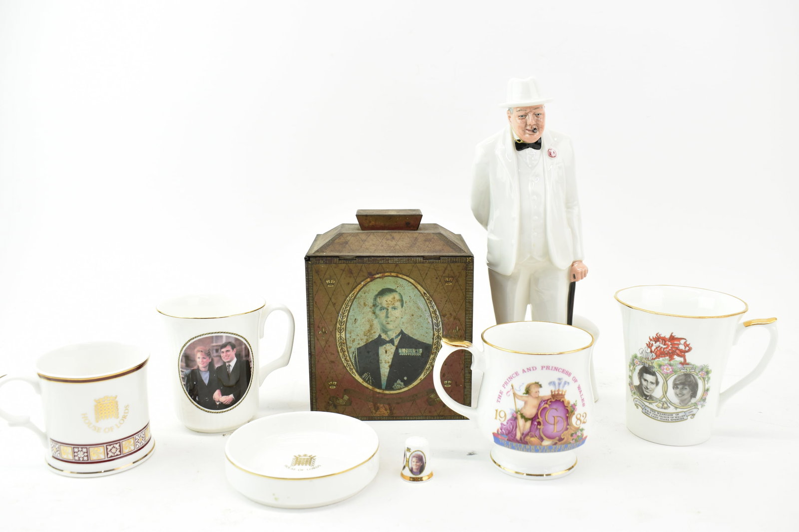 Royal Doulton Winston Churchill Figure: Royal Doulton Winston Churchill FigureRoyal Doulton Winston Churchill Figure together with commemorative cups, pin dish, thimble, and tea tin. Figure is used condition but generally very good, having