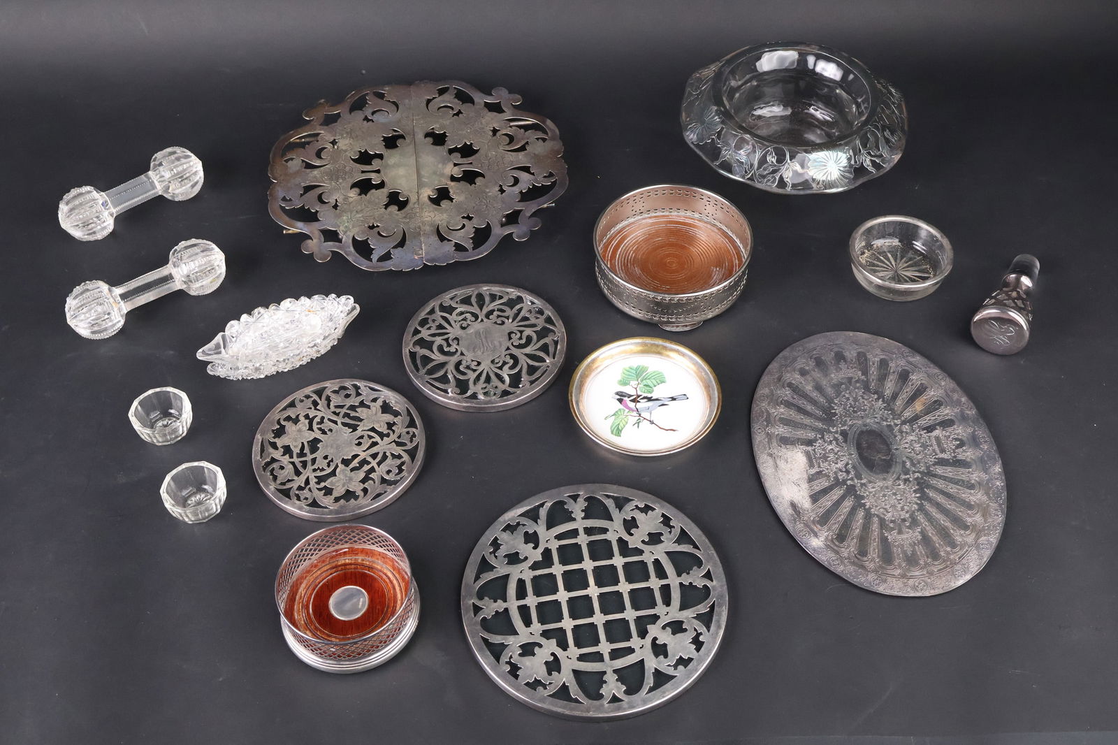 Two Sterling Silver and Glass Trivets: Two Sterling Silver and Glass TrivetsTogether with three silver plated trivets, a sterling silver and wood coaster, a Lenox plated wine bottle holder, a plated bird decorated coaster, a glass dish, gl