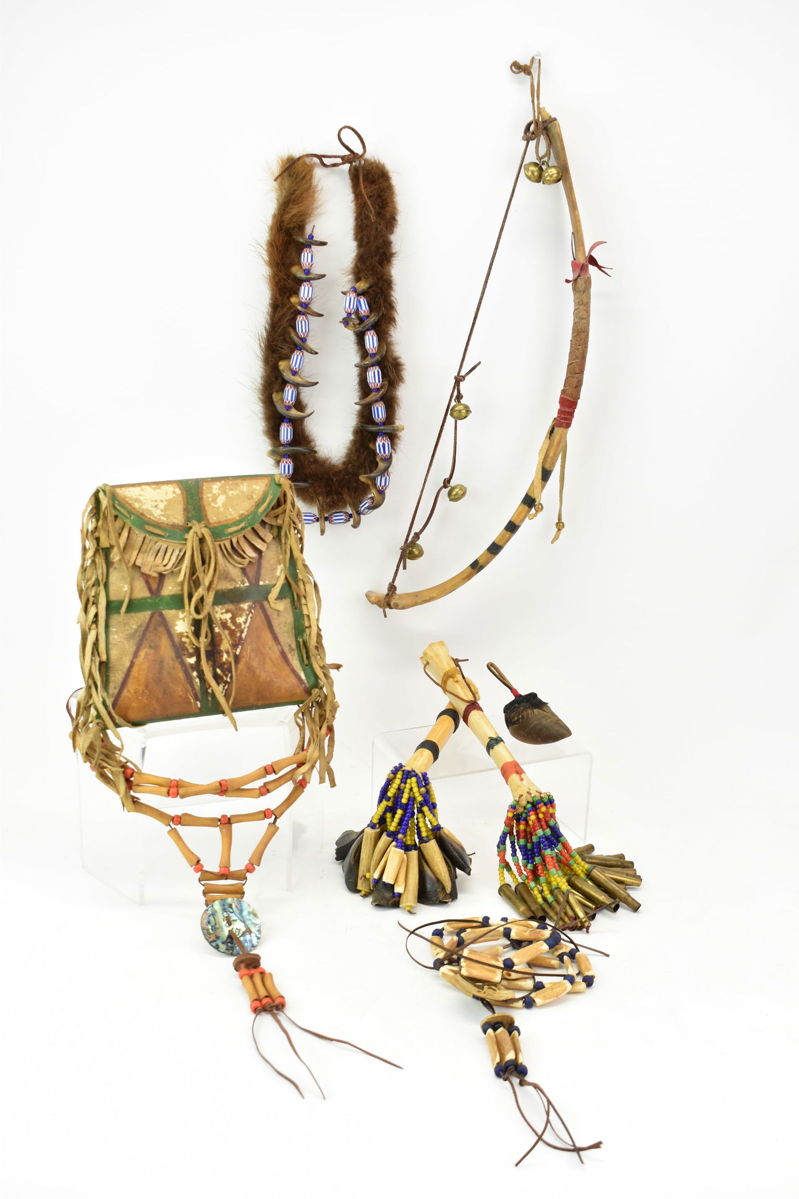 Group of Assorted Native American Articles: Group of Assorted Native American ArticlesGroup of Assorted Native American Articles comprising of diminutive bone recurve bow, leather satchel, bone handled beaded and bullet case rattle, bear claw n
