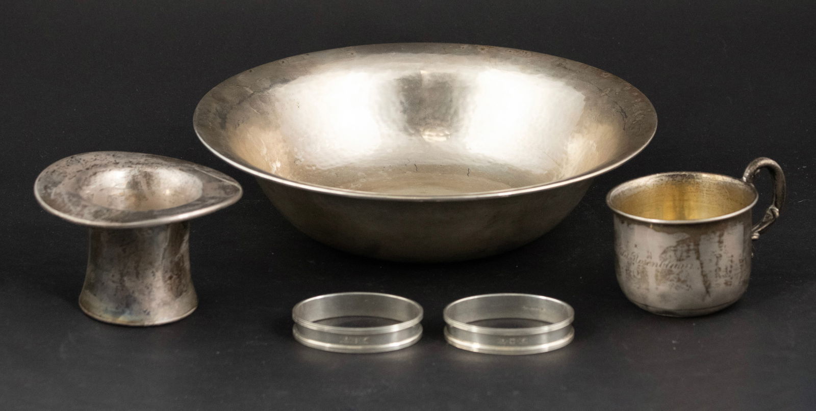 Sterling Silver Hand Hammered Bowl: Sterling Silver Hand Hammered Bowl9"dia. Together with two sterling silver napkin rings, a sterling top hat, and a sterling silver baby cup. Approx. 15 t.o.9 in. (22.9 cm.)