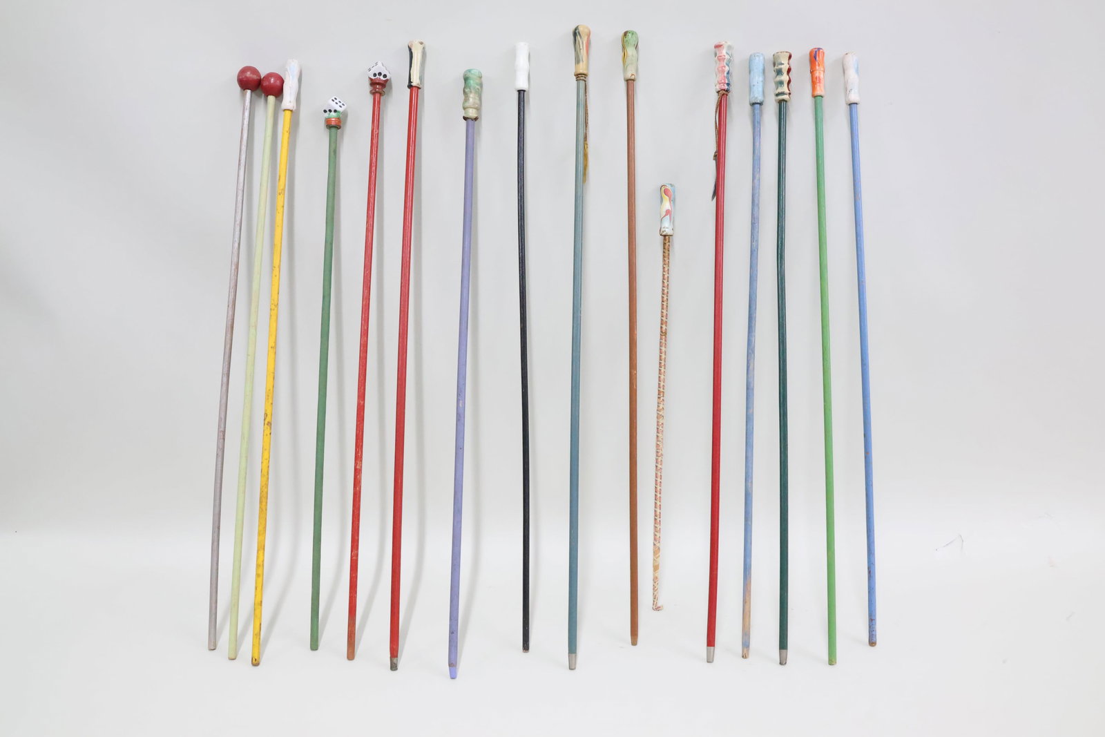 Vintage Group of Sixteen Carnival Canes: Vintage Group of Sixteen Carnival Canes Vintage Group of Sixteen Carnival Canes. Including 2 porcelain dice, 2 wood red balls and 12 multi-colored wooden handles. Longest cane measures 36 3/4" long. U