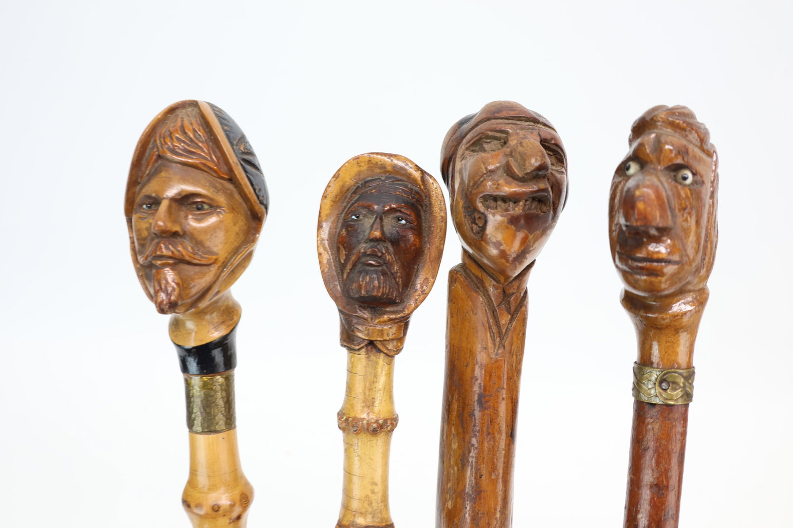 Four Carved Figural Faced Walking Sticks: Four Carved Figural Faced Walking Sticks Four Carved Figural Faced Walking Sticks. Comprising man with grotesque face, one with man's face having large nose and glass eyes, one of conquistador with