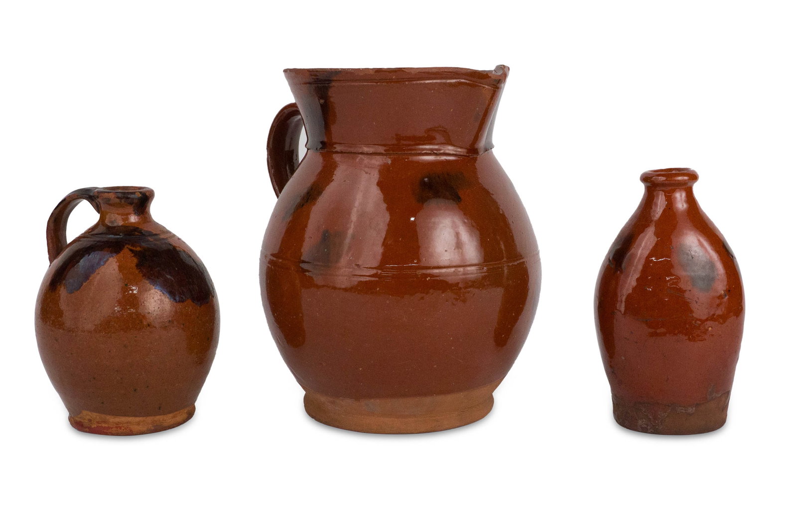 Three Redware Vessels: Three Redware Vessels American, 19th C. Comprising a pitcher, small handled jug and bottle. Provenance: Property of a Private Bernardsville, NJ Collection Heights from 6 in. (15.2 cm.) to 8 1/2 in.