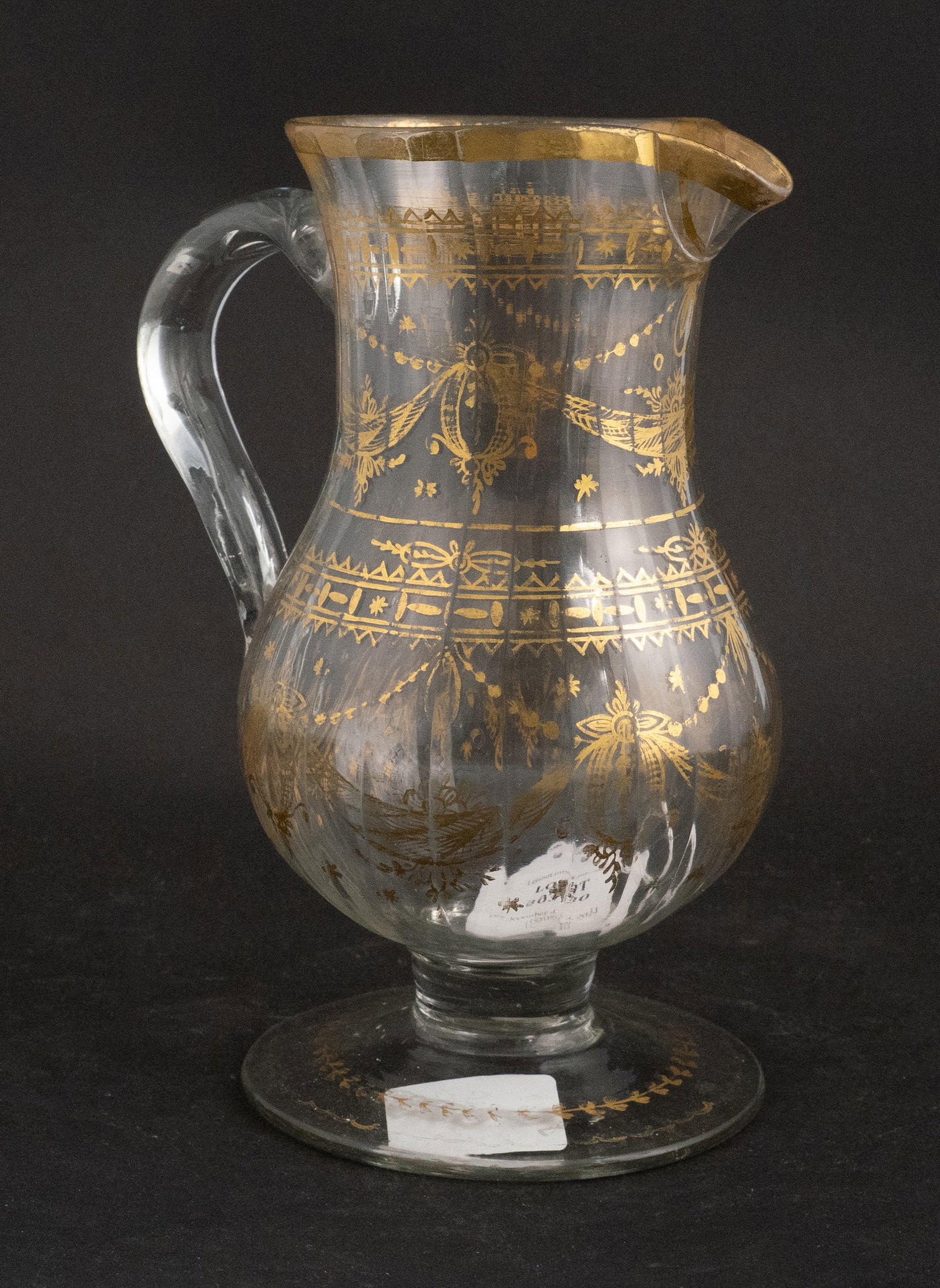 18th Century German Gilt-Decorated Glass Wine Pitcher: 18th Century German Gilt-Decorated Glass Wine Pitcher Circa 1740, clear blown glass with fluted motif and applied handle, all over gilt floral and swag motifs, conical foot, rough pontil. Rubbing and 