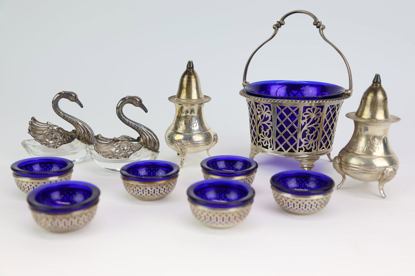 Group of Assorted Silver Table Articles: Group of Assorted Silver Table Articles Group of Assorted Silver Table Articles. Comprising Master Salts with cobalt liners, pair of Swan salts, Cobalt lined sugar bowl. Together with a pair of
